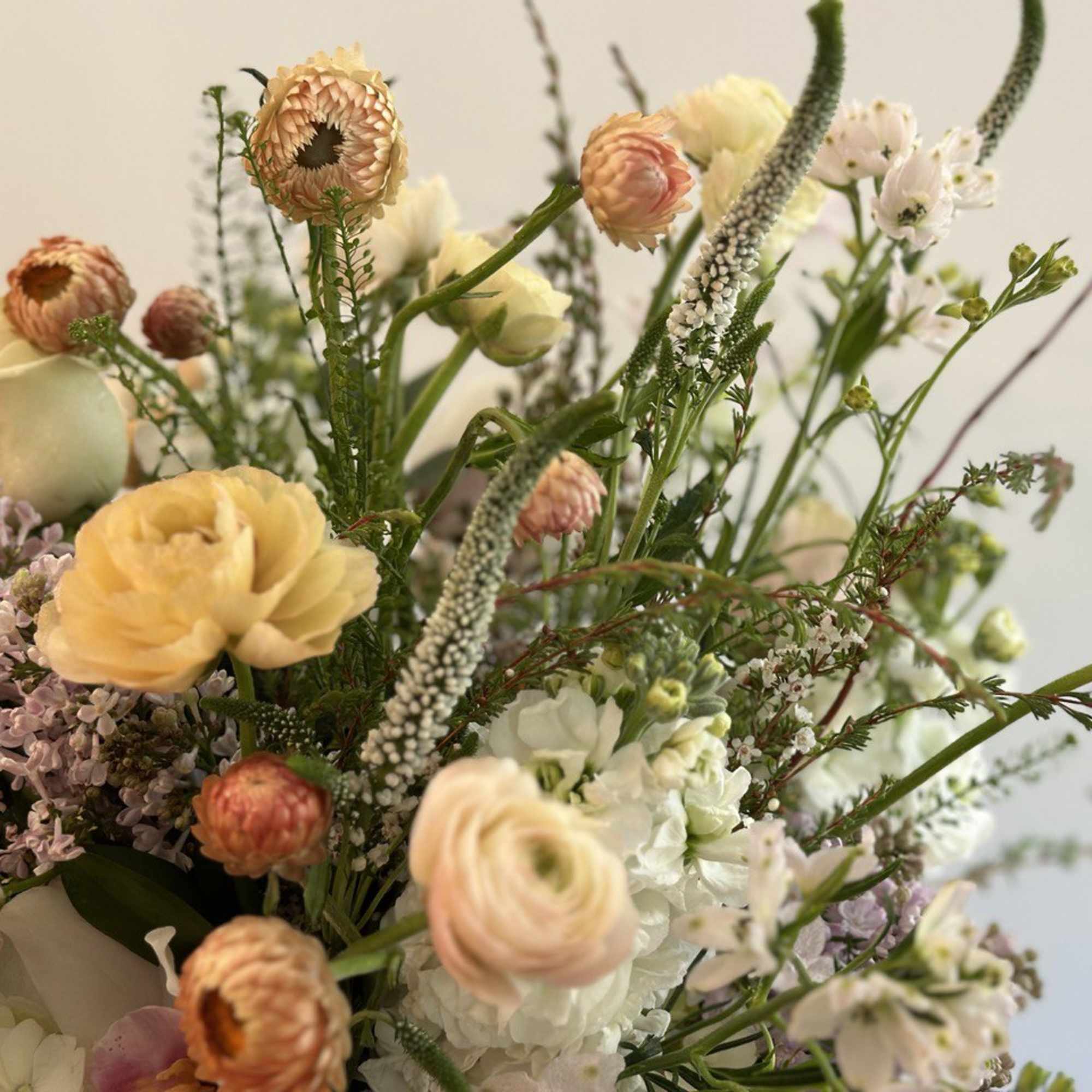 Loose pastel arrangement of ranunculus, roses, and mixed blooms in a soft garden style