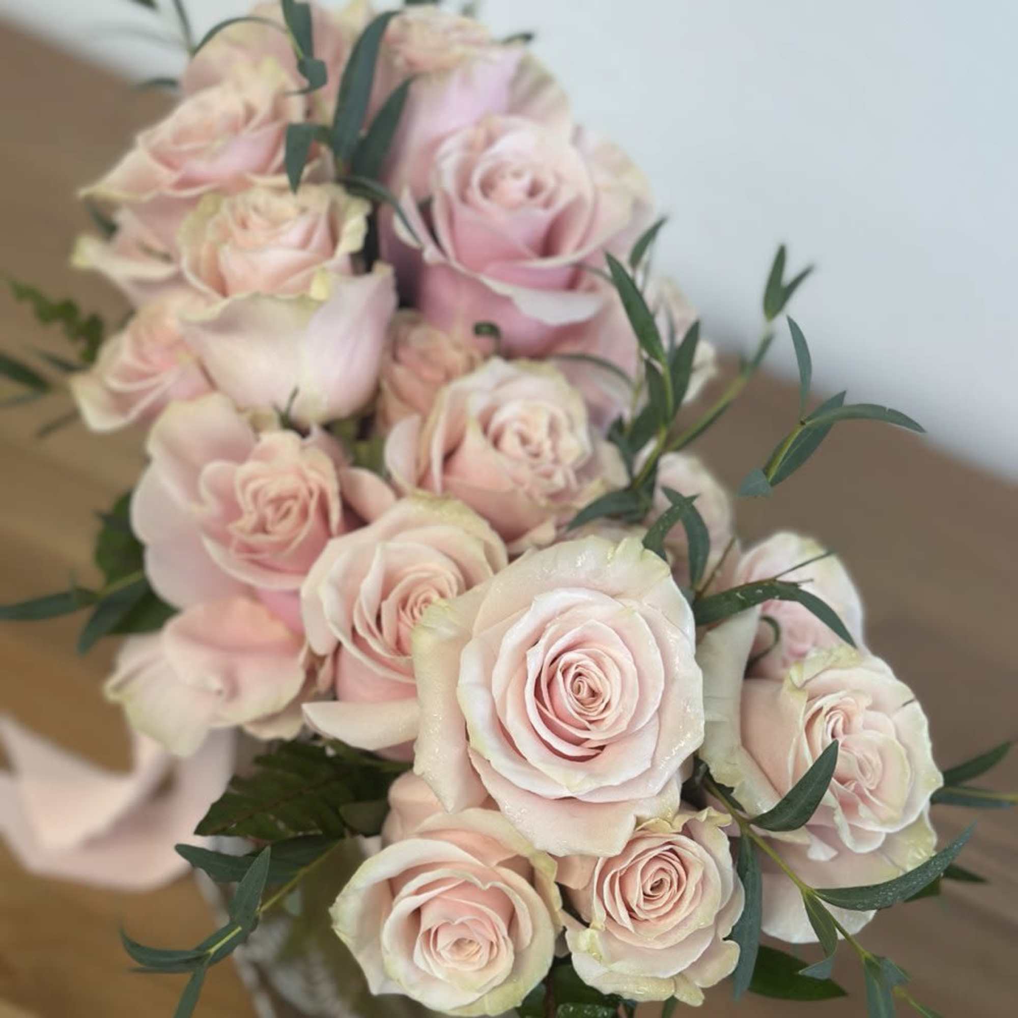 Bouquet of pale pink roses with greenery in a glass vase