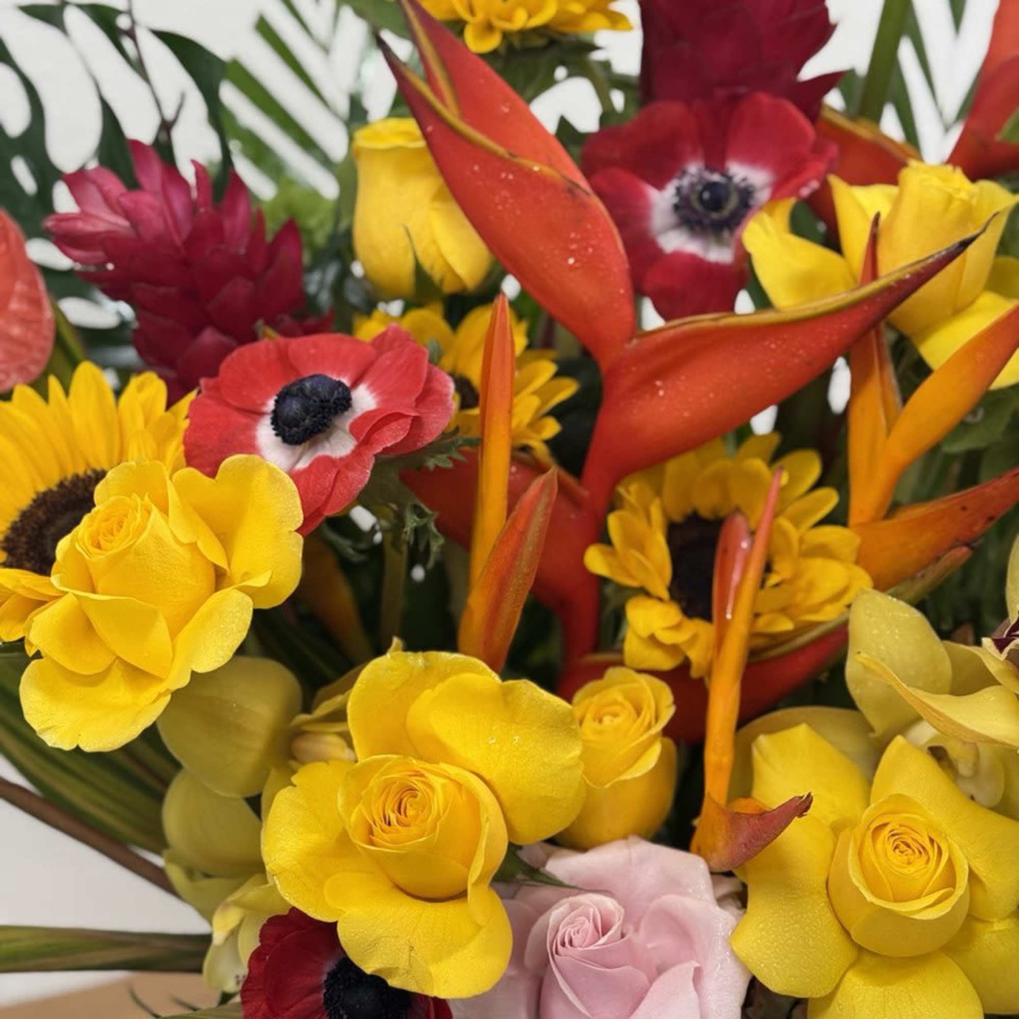 Bright mixed bouquet with yellow roses, sunflowers, and red tropical blooms