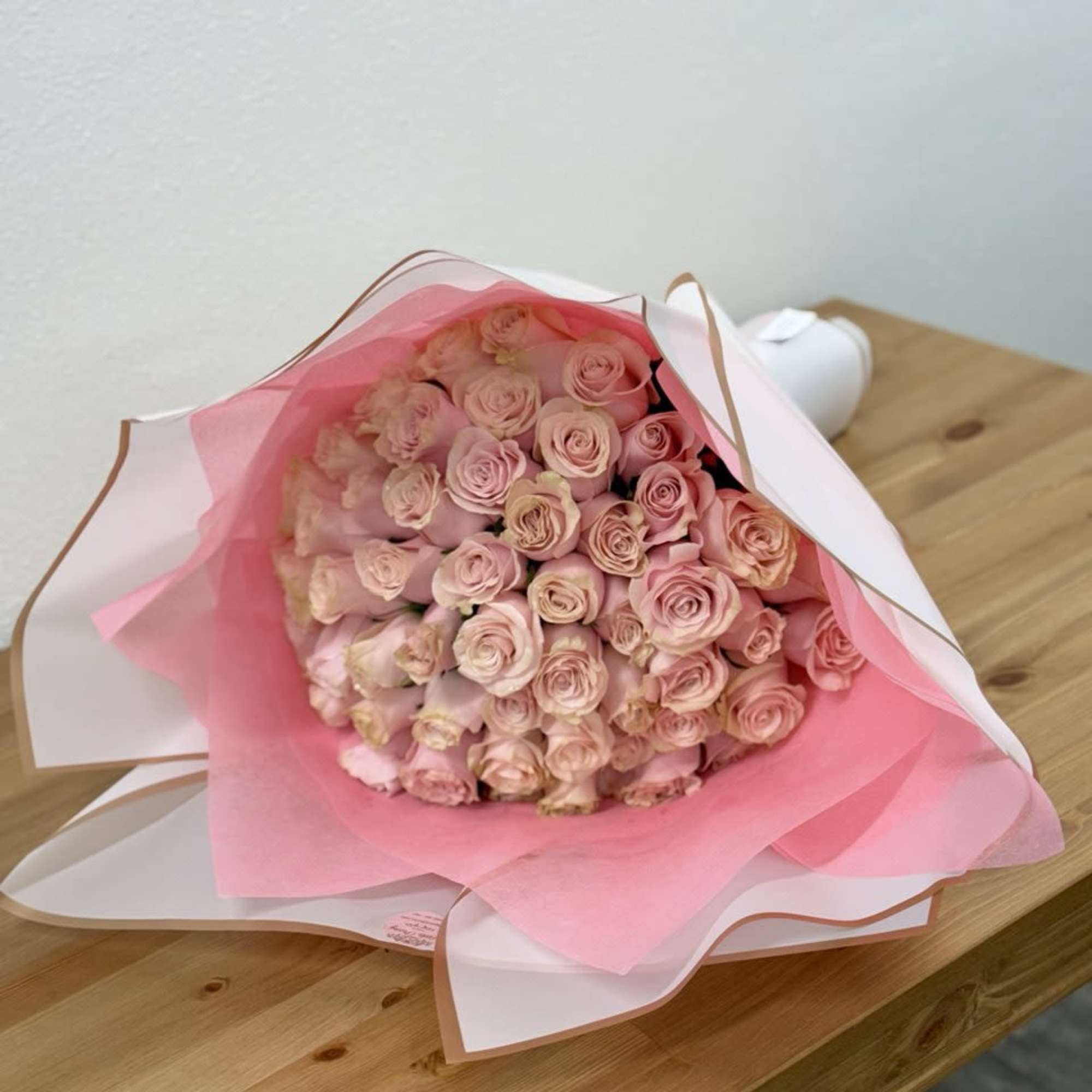Bouquet of pale pink roses wrapped in pink and white paper