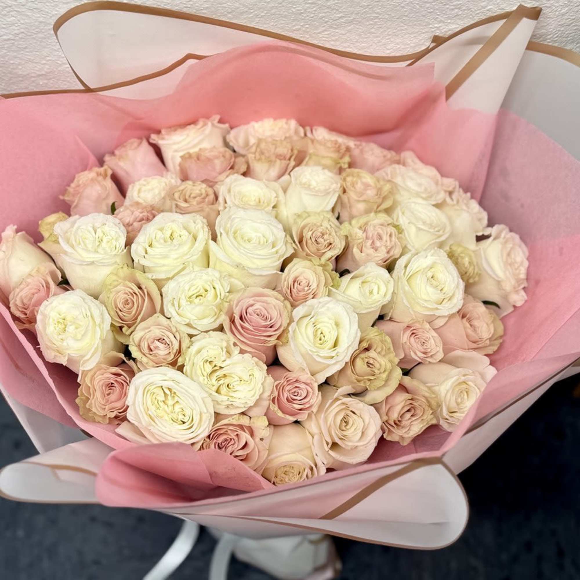 Bouquet of pale pink and cream roses wrapped in pink paper