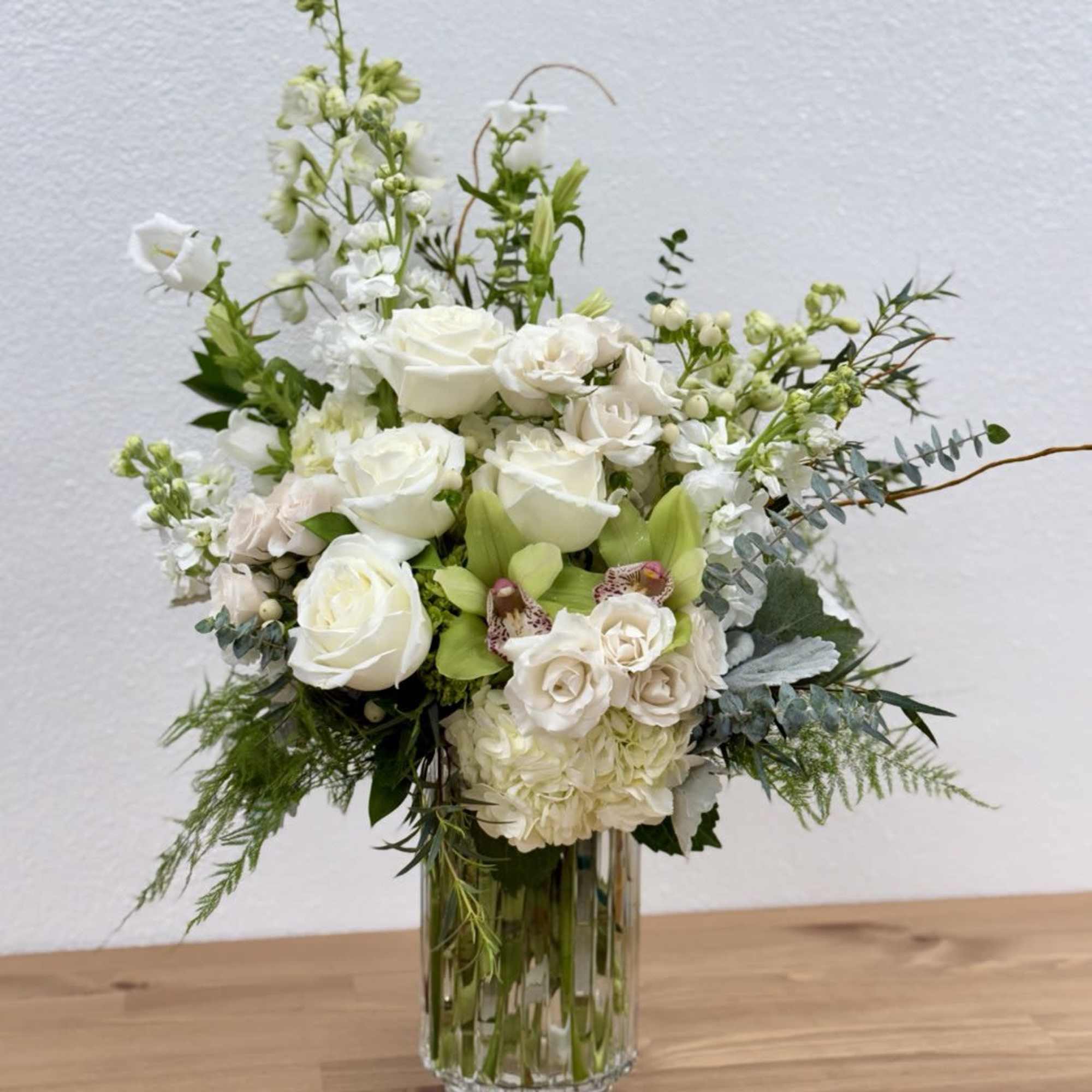 White floral arrangement in a clear glass vase with mixed blooms and greenery