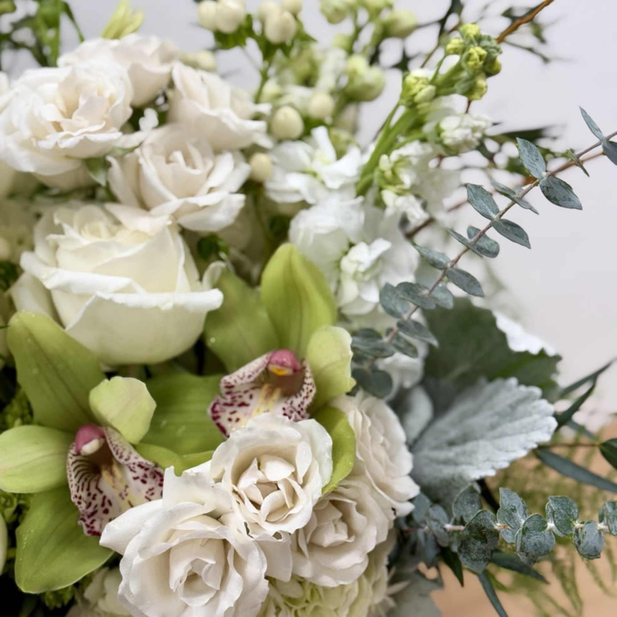 White floral bouquet with green orchids and blue-gray foliage
