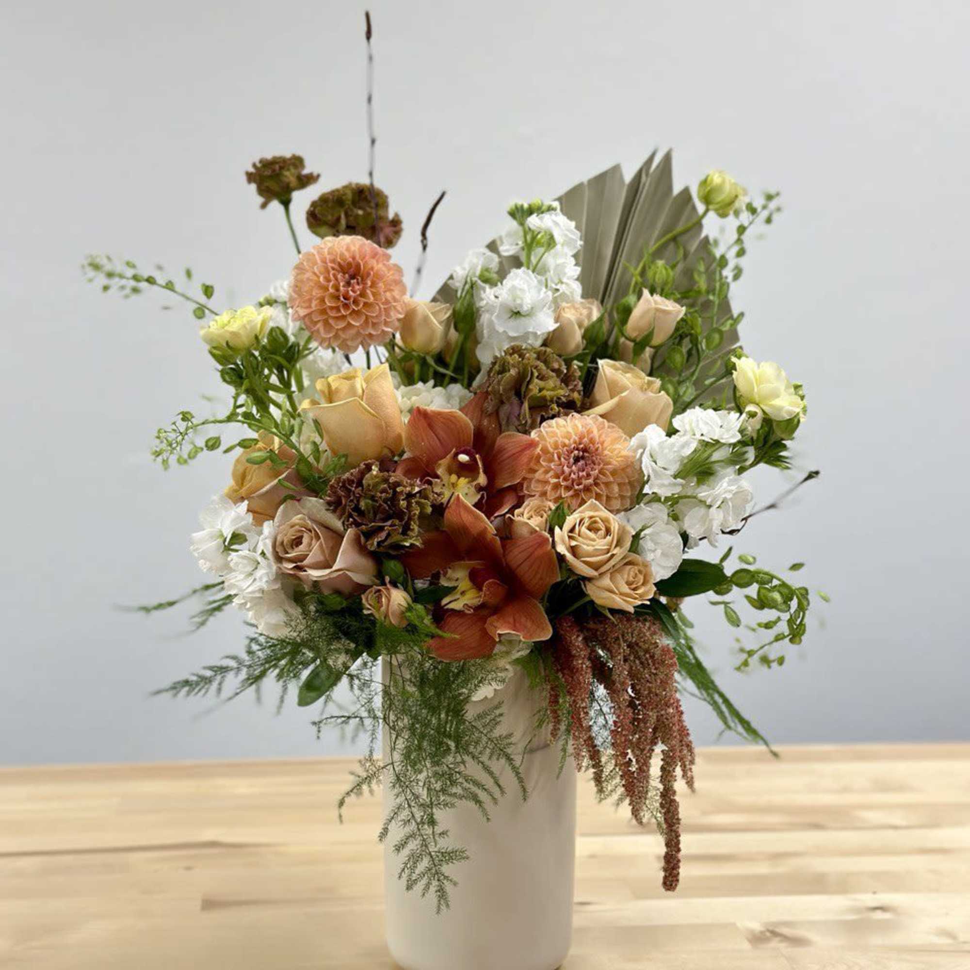 Peach and white floral arrangement in a white vase