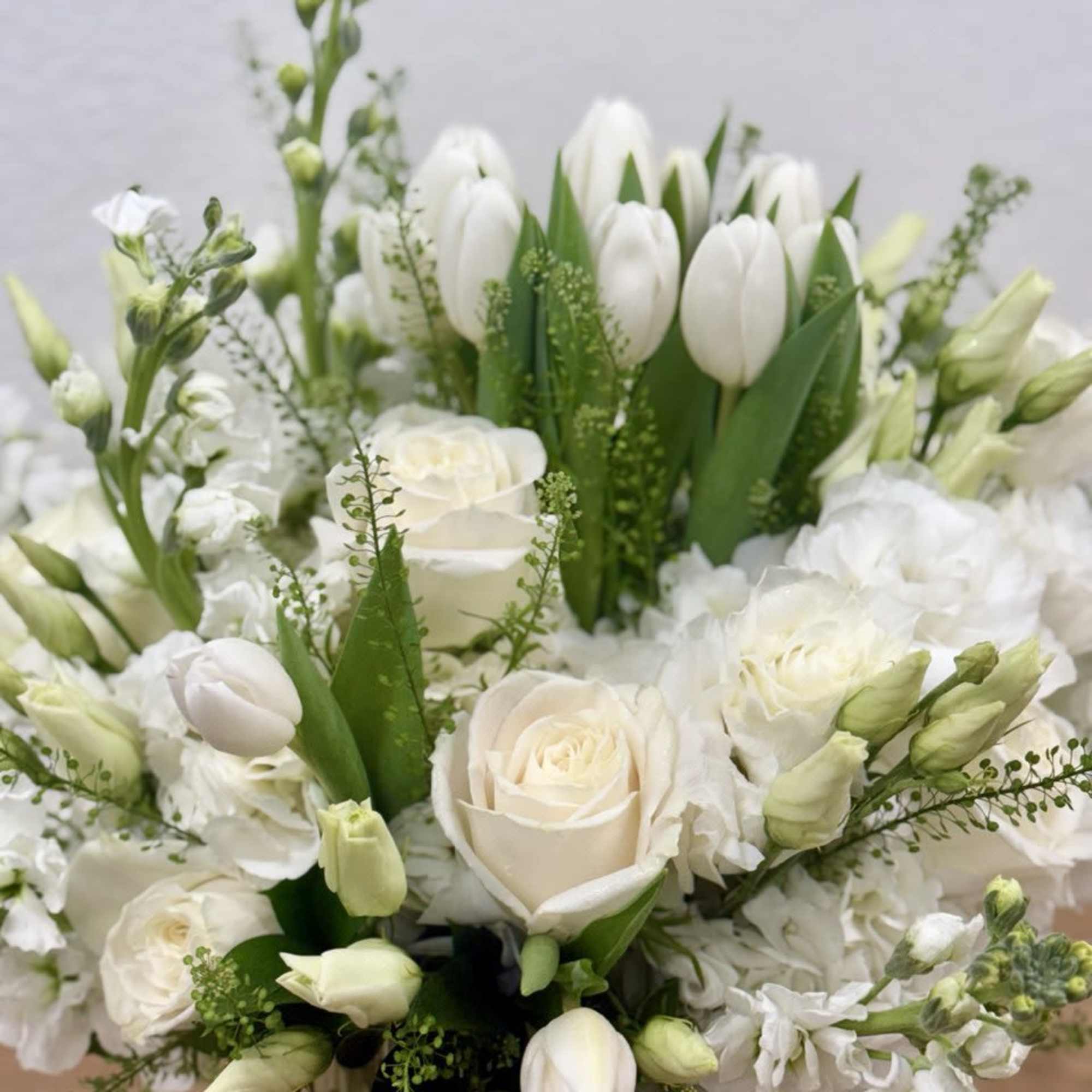 White tulips and roses arranged in a clear vase