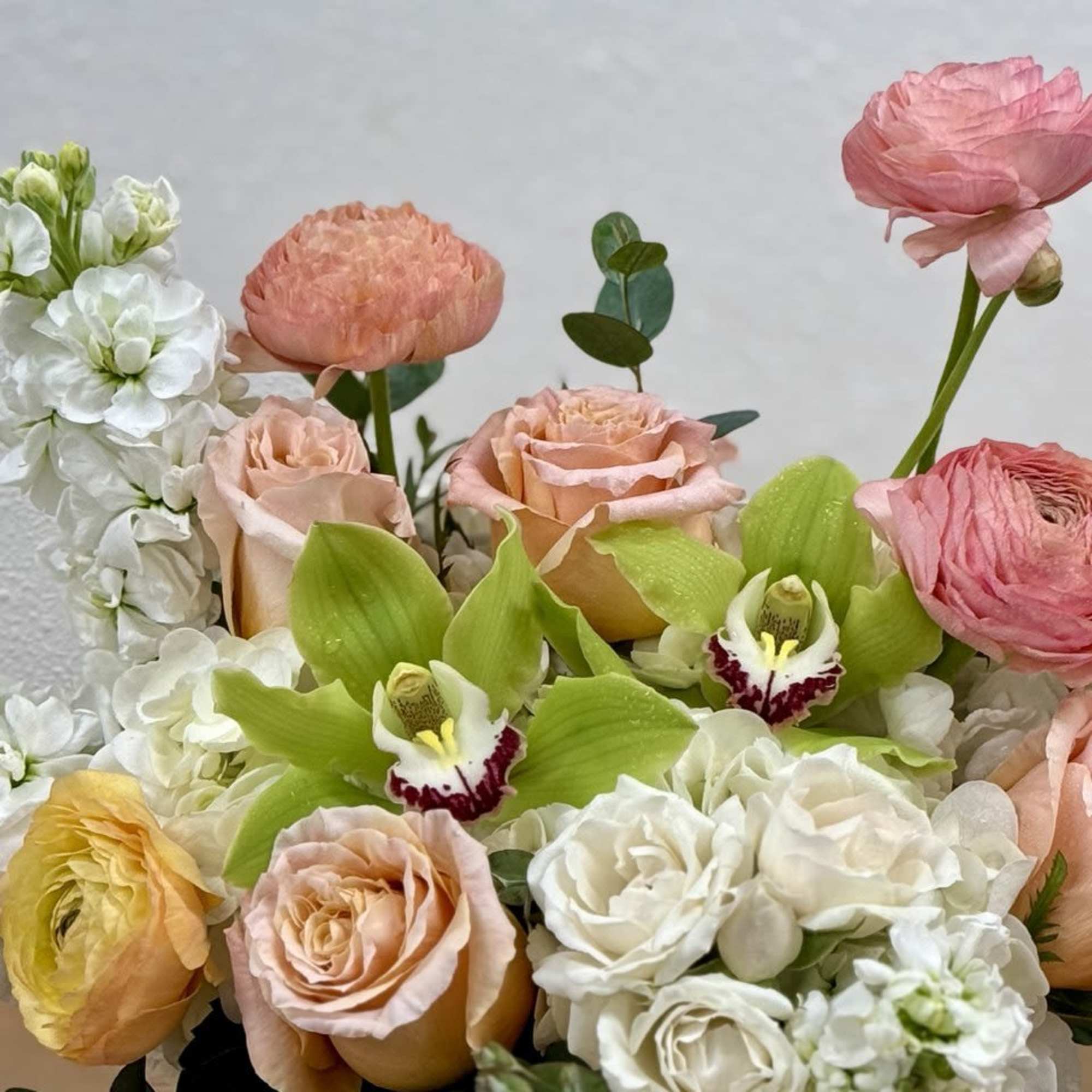 Bouquet of peach, pink, and white flowers with green orchids