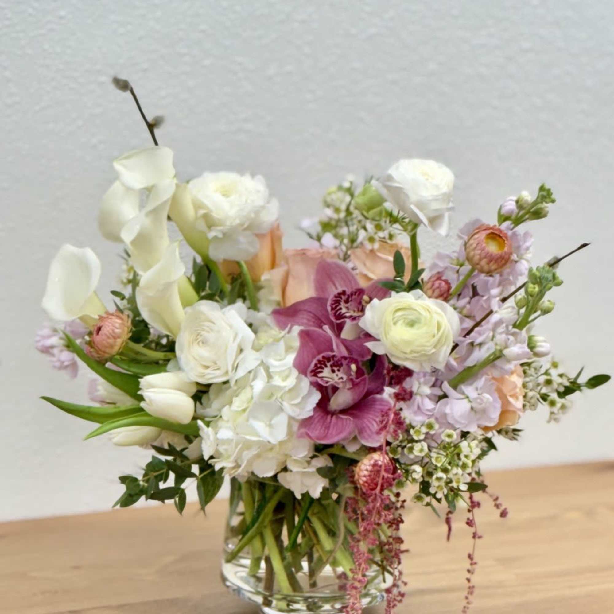 Mixed bouquet in a clear glass vase with white, pink, and peach flowers