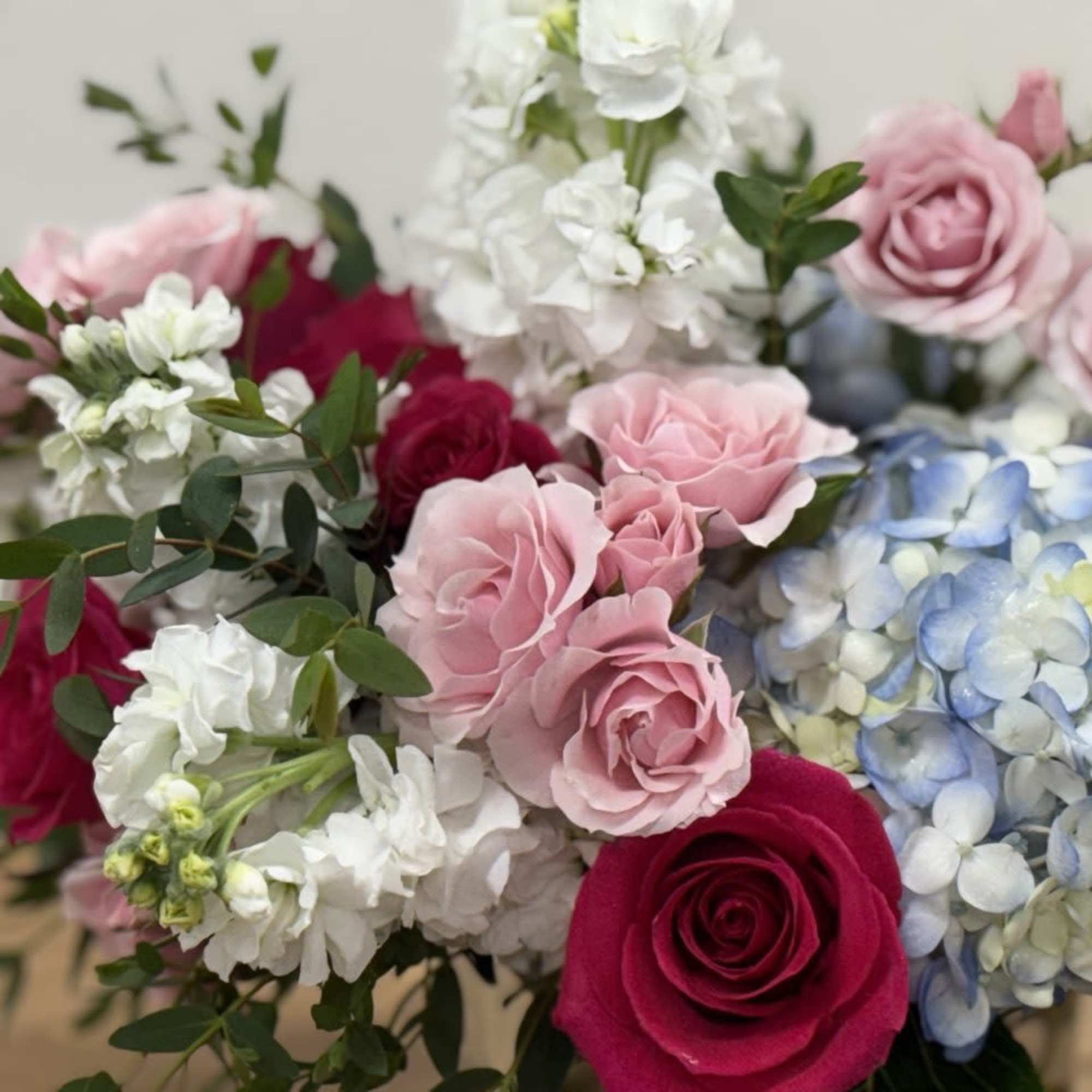 Bouquet of pink and red roses with white flowers and blue hydrangeas