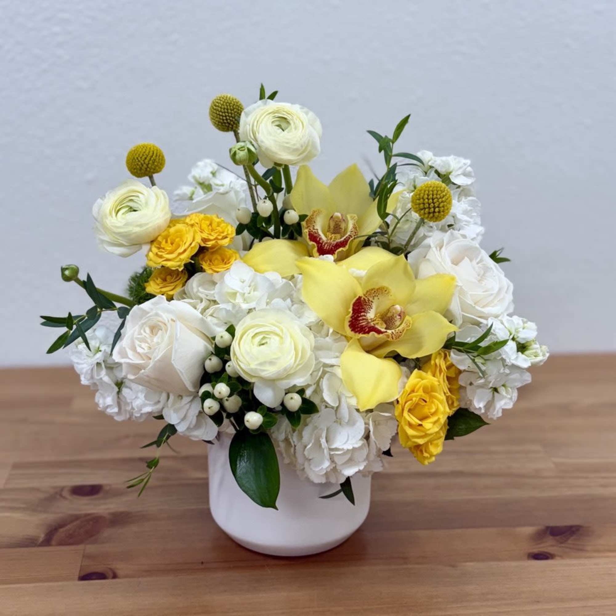 White and yellow floral arrangement in a white vase