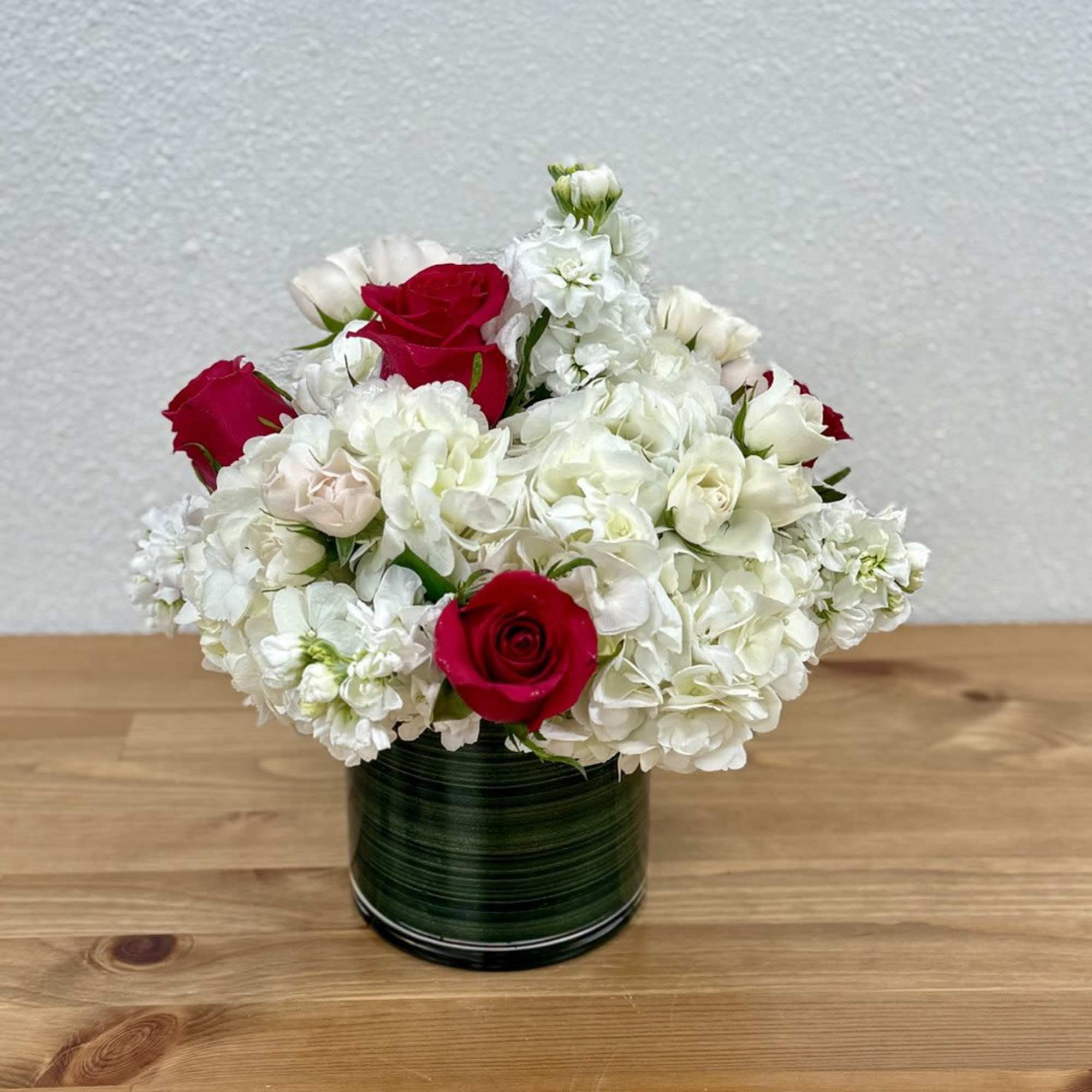 Red roses and white hydrangeas arranged in a green vase