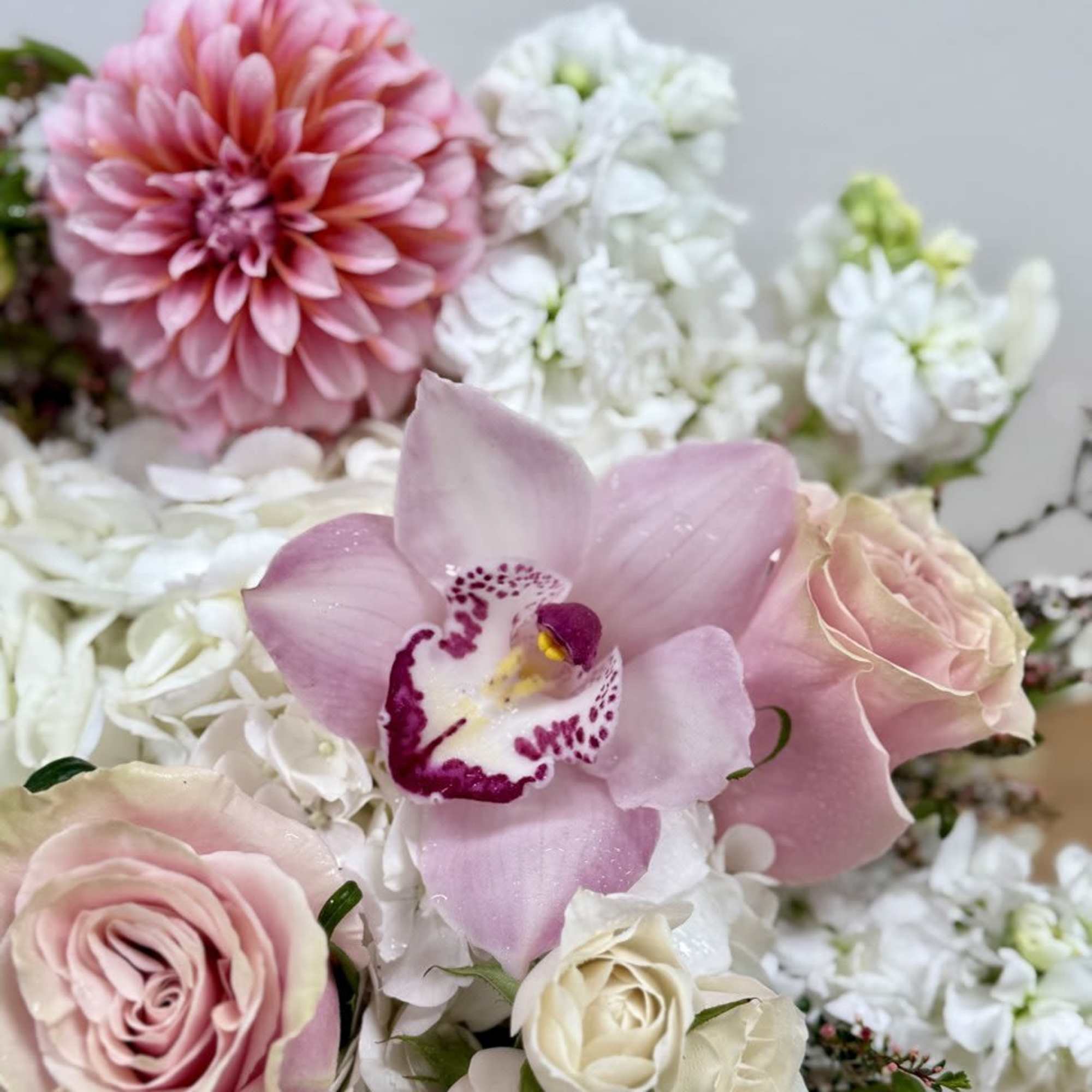 Pink roses and a pink orchid among white flowers in a bouquet