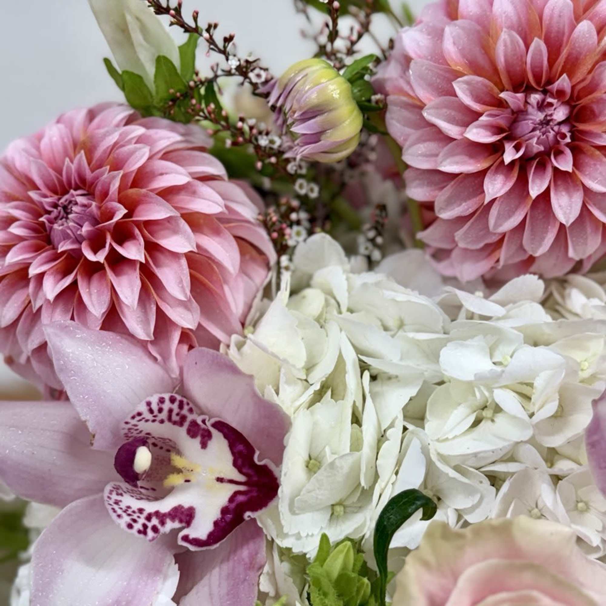 Pink dahlias, white hydrangeas, and a pink orchid in a bouquet