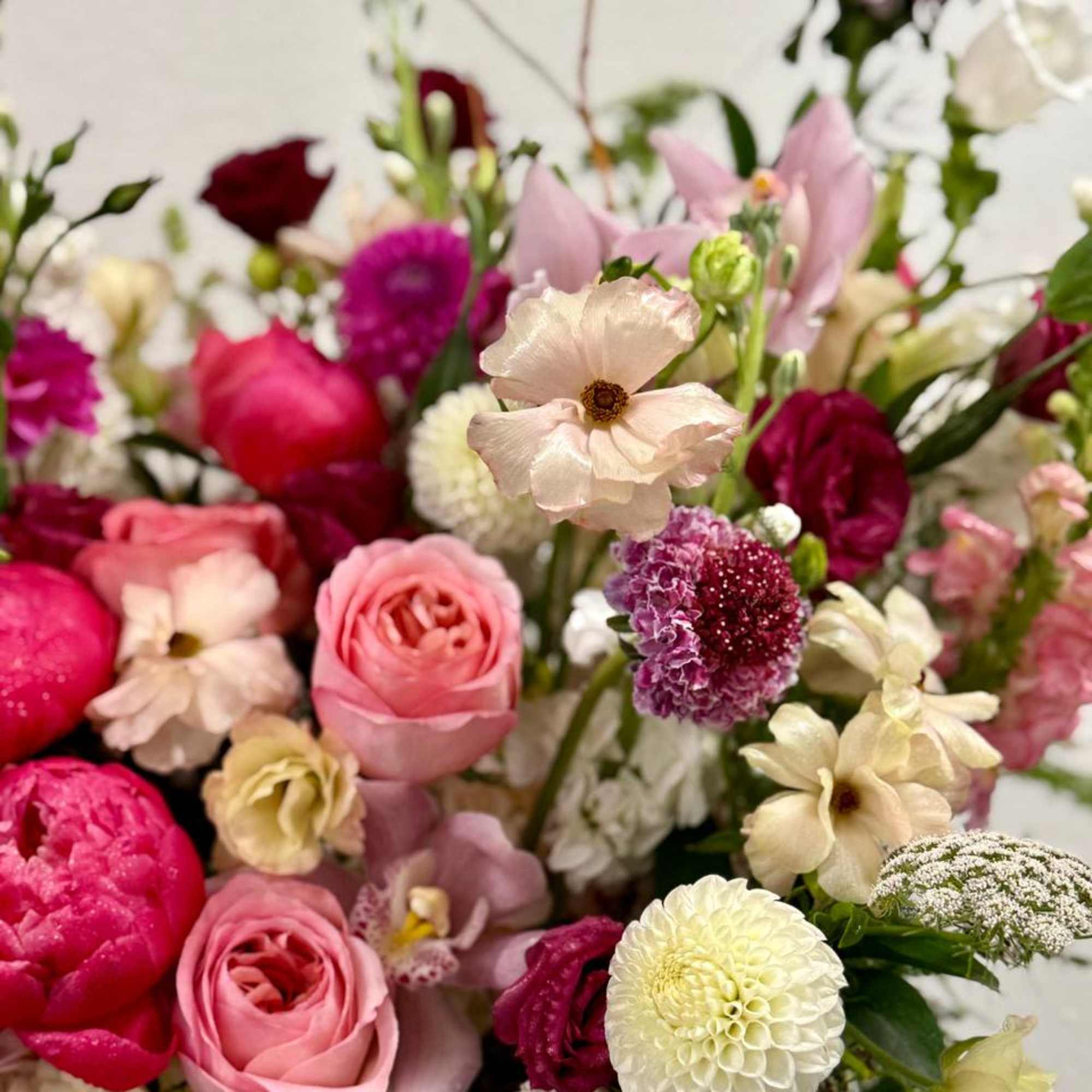 Lush arrangement of pink roses, bright peonies, and white dahlias with mixed accent blooms