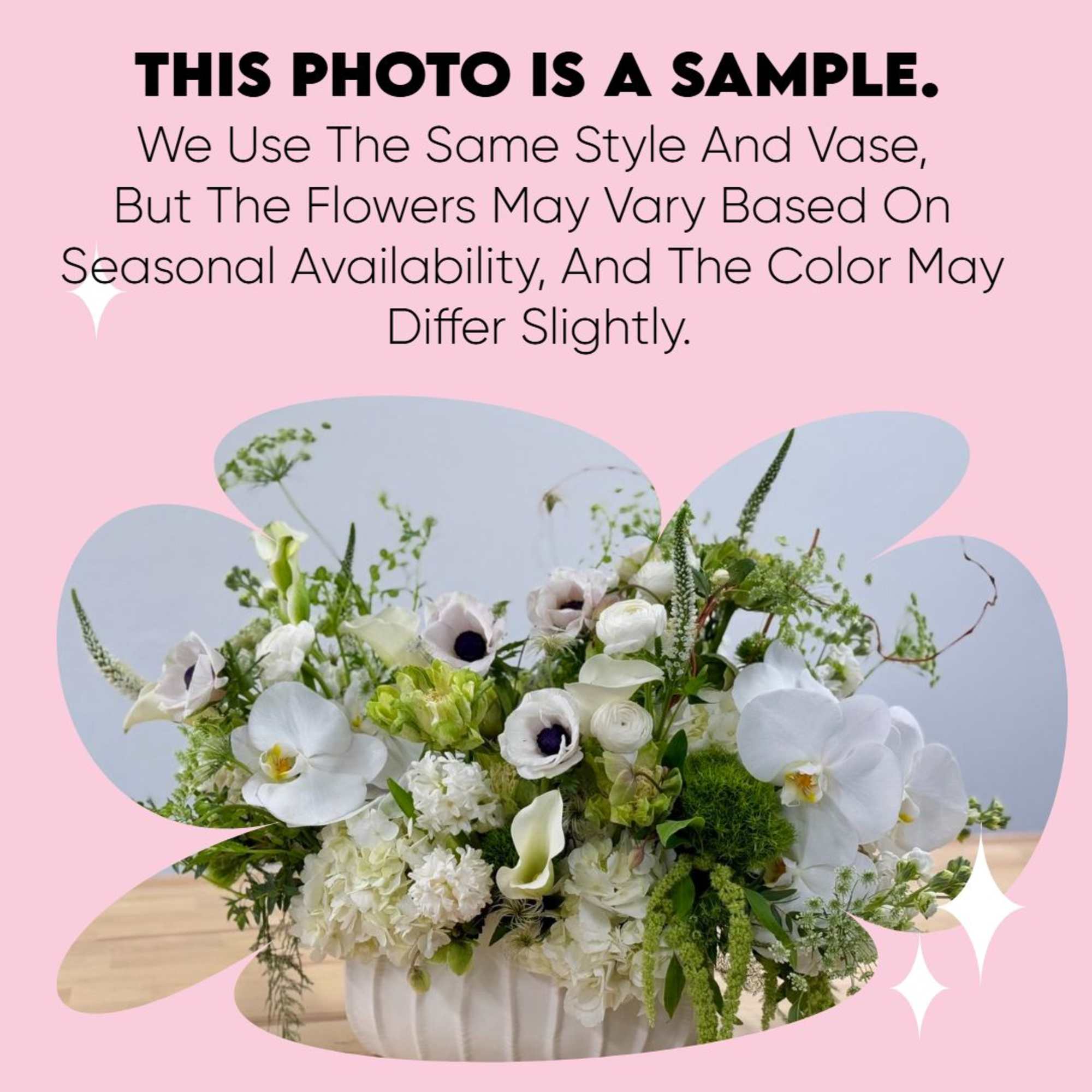 Low white and green flower arrangement with orchids, anemones, and calla lilies in a white ceramic bowl vase