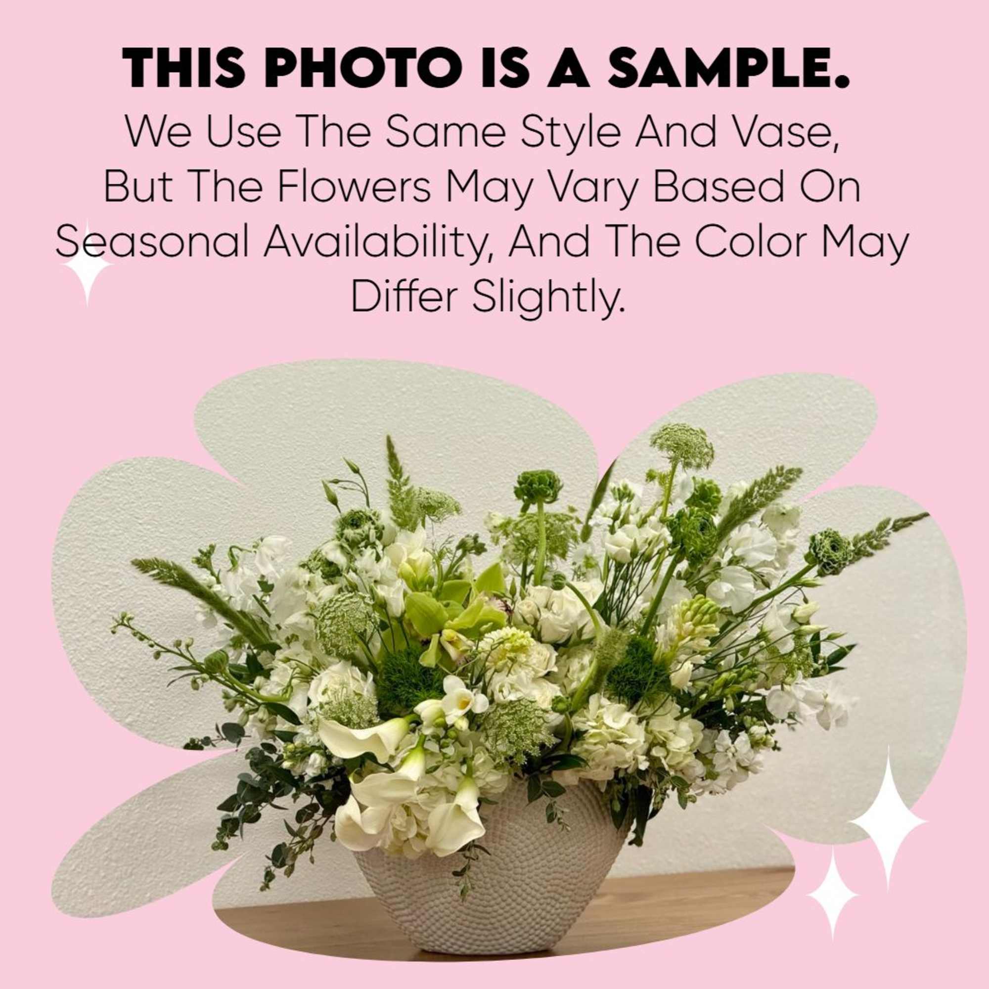 Low white and green flower arrangement in a textured white bowl-shaped vase.