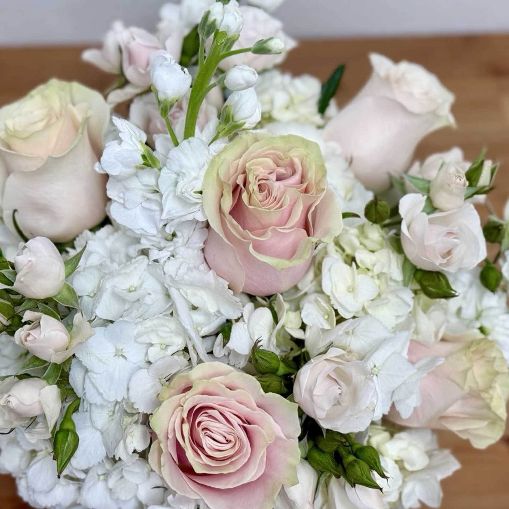 Bouquet of pale pink roses and white flowers on a wooden surface