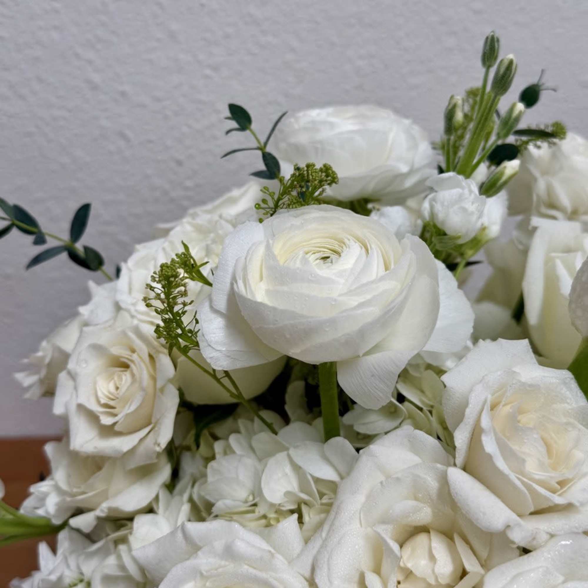 White rose and ranunculus bouquet with small green accents