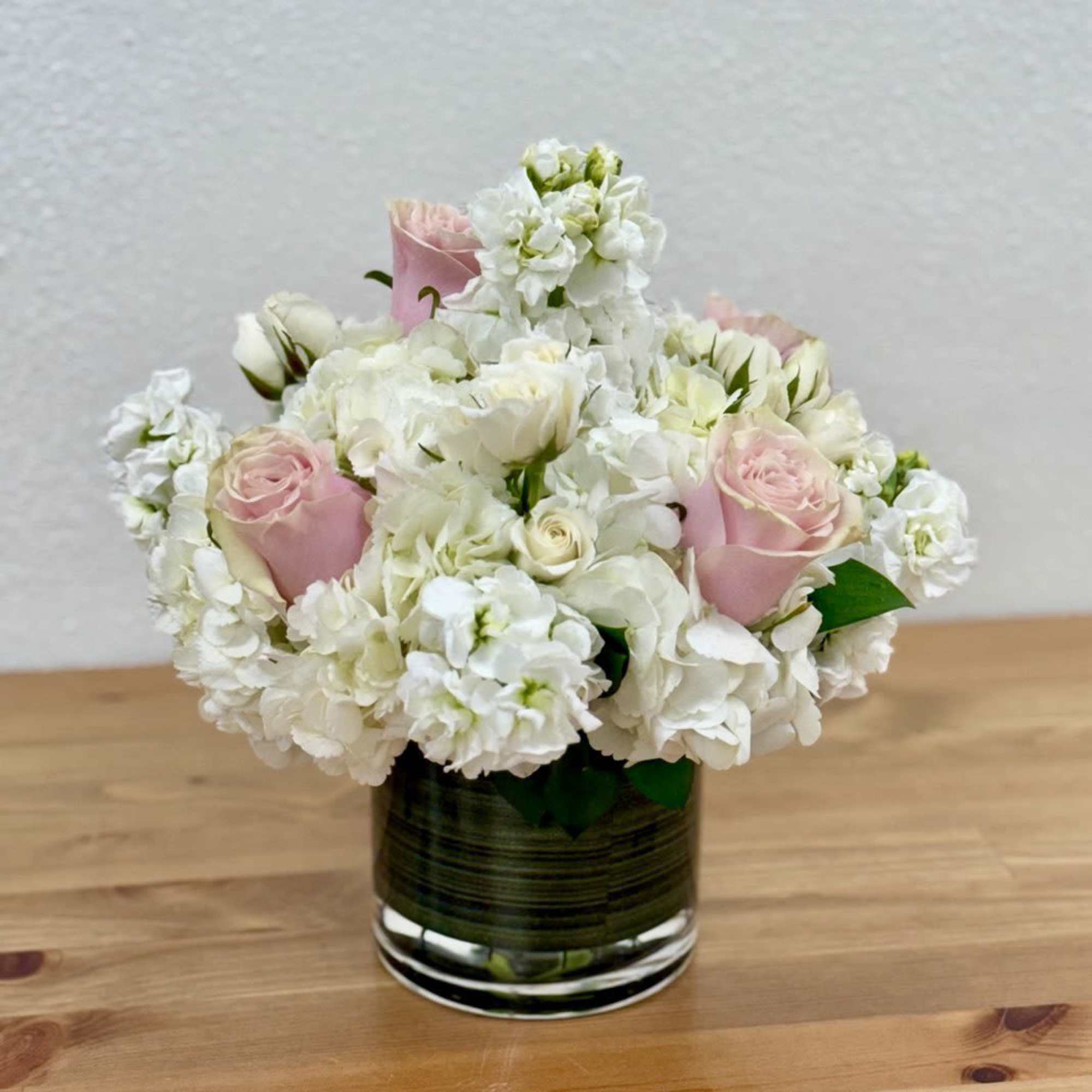 Pink roses and white flowers arranged in a glass vase