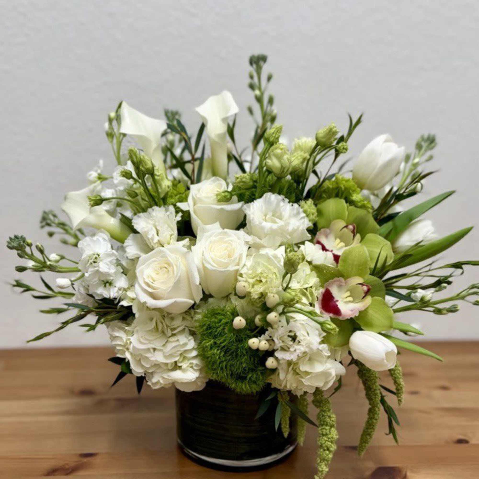 White and green floral arrangement in a black vase