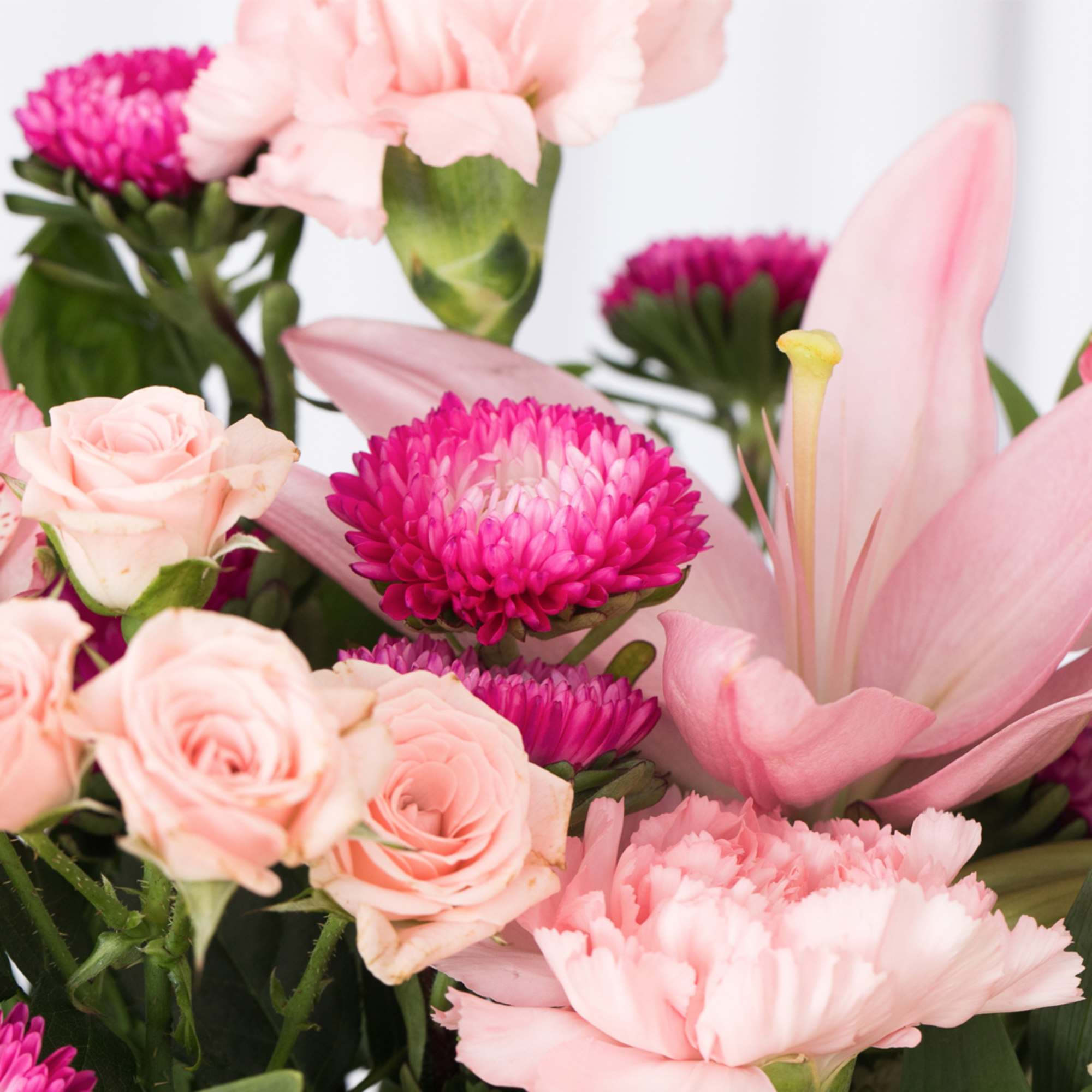 Pink bouquet of roses, carnations, lilies, and bright fuchsia mums in a mixed arrangement