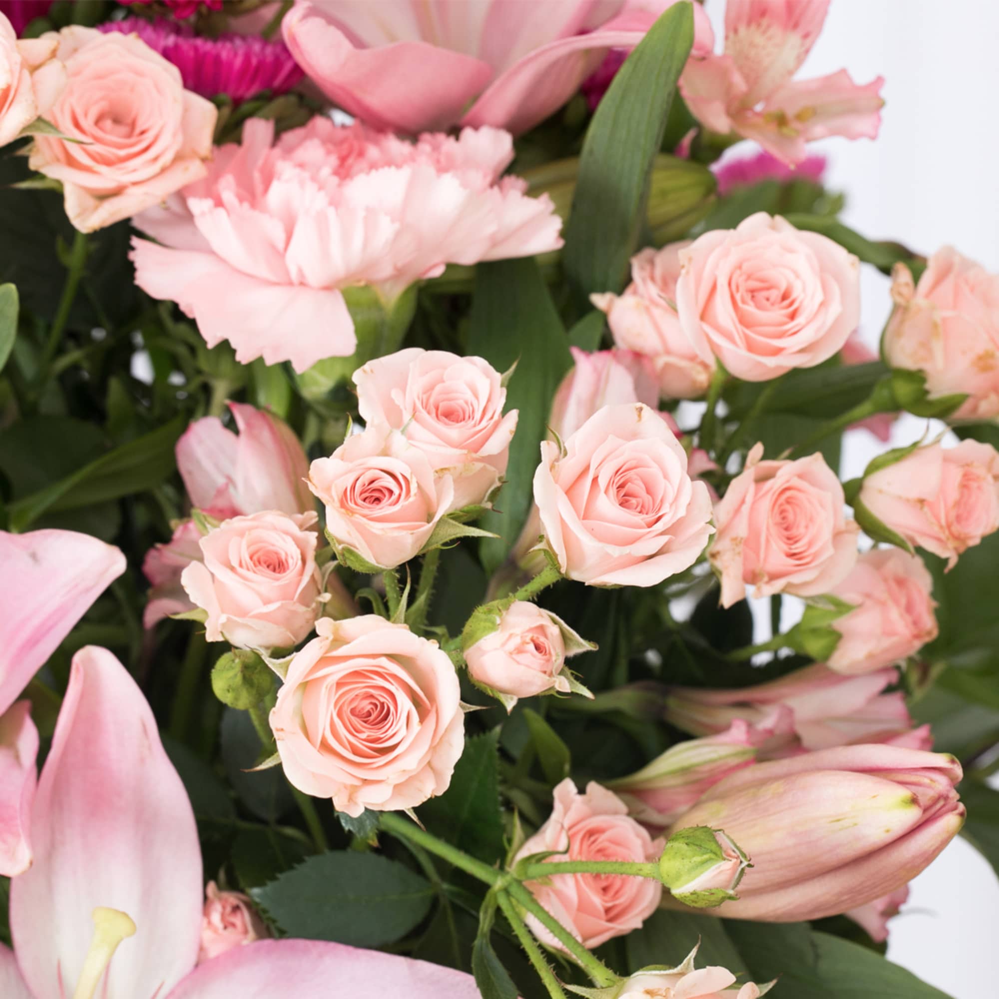 Close-up of a pink bouquet with roses, lilies, carnations, and other mixed flowers.