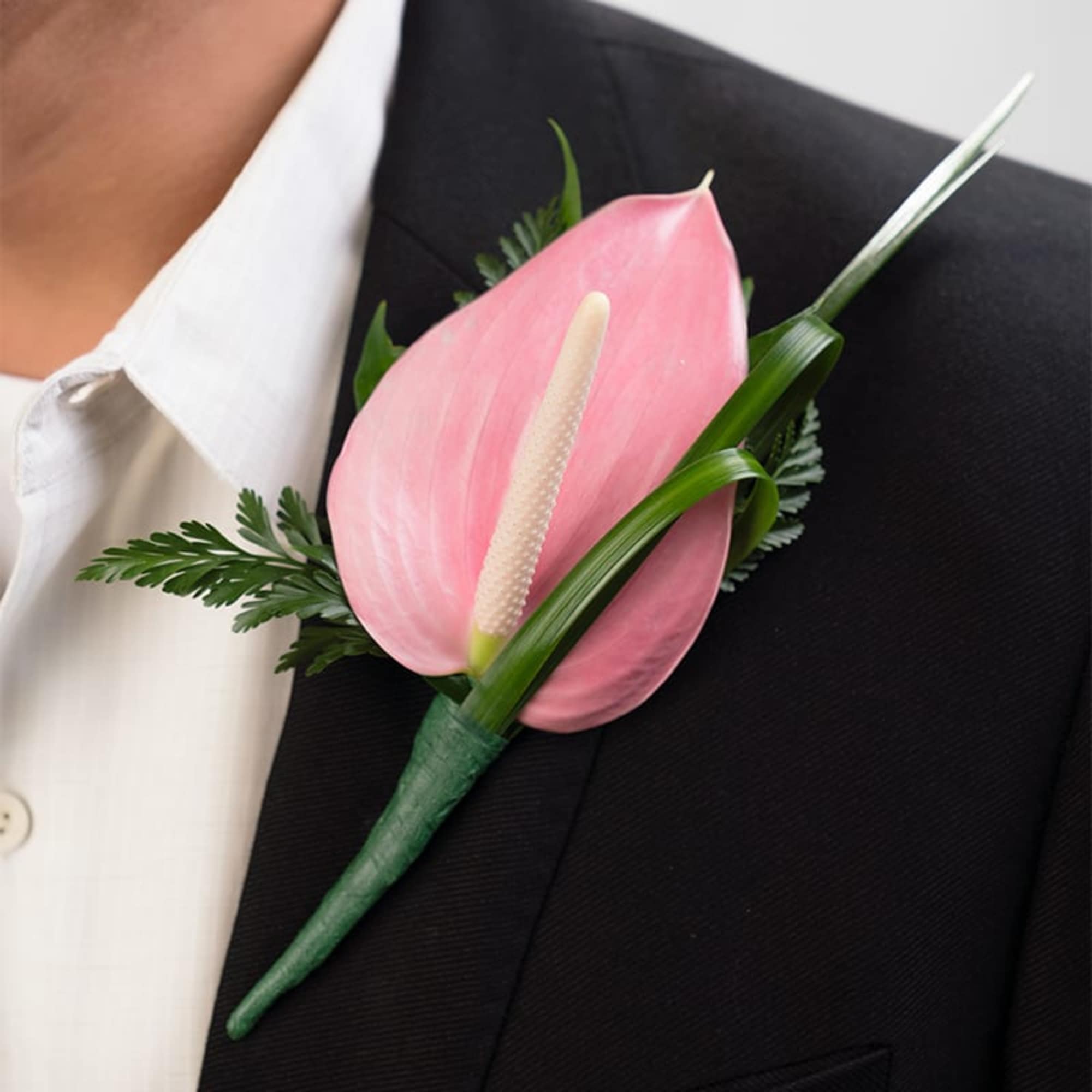 Pink tropical boutonniere pinned to the lapel of a black suit jacket