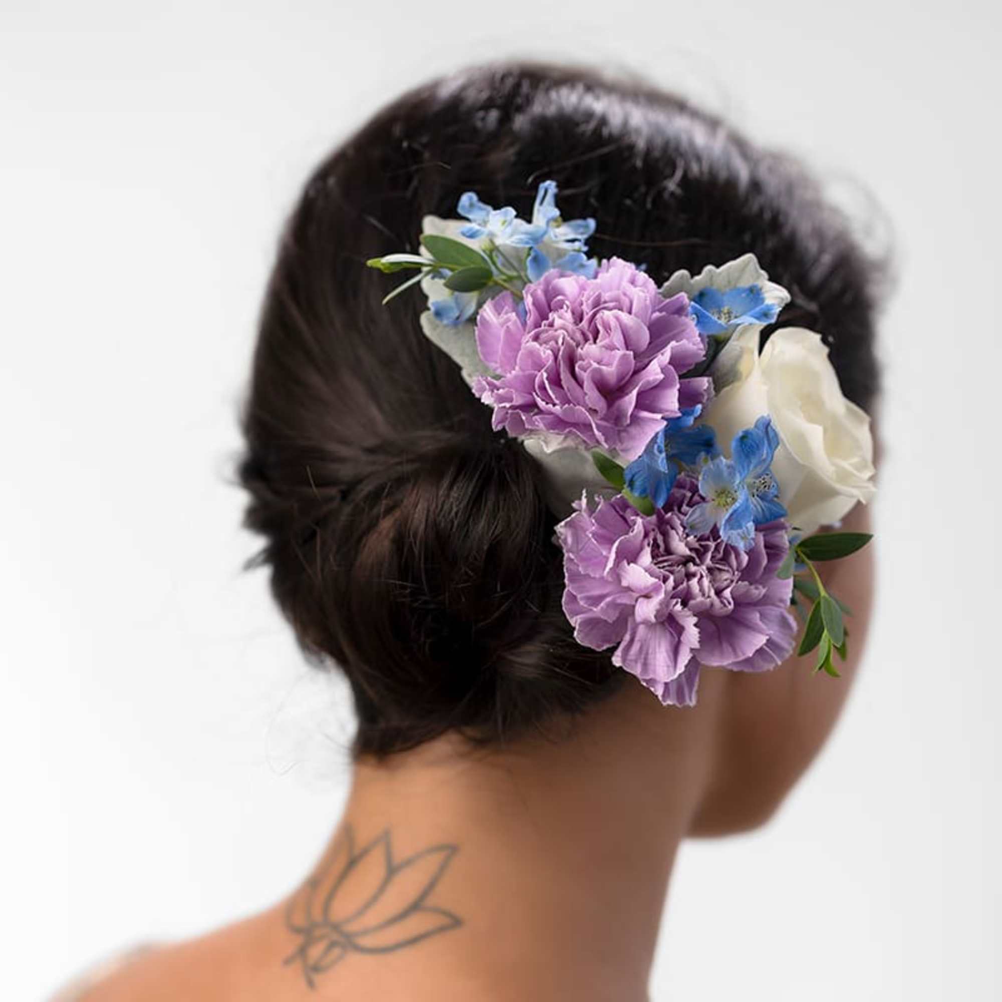 Floral hairpiece with purple, blue, and white blooms in a dark hair updo