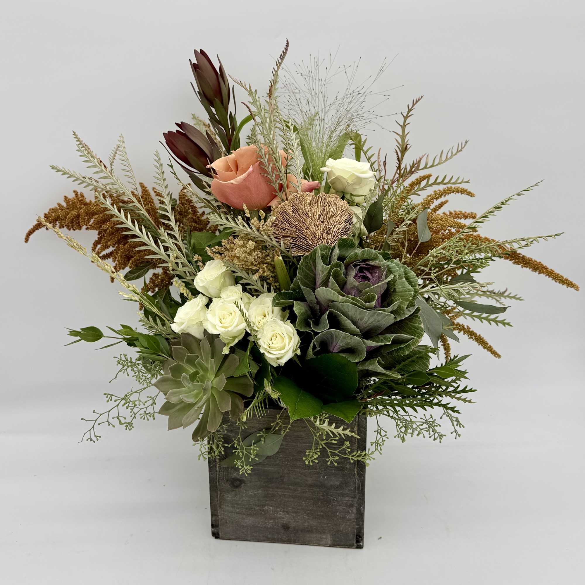 Mixed floral arrangement in a rustic wooden box with roses and greenery