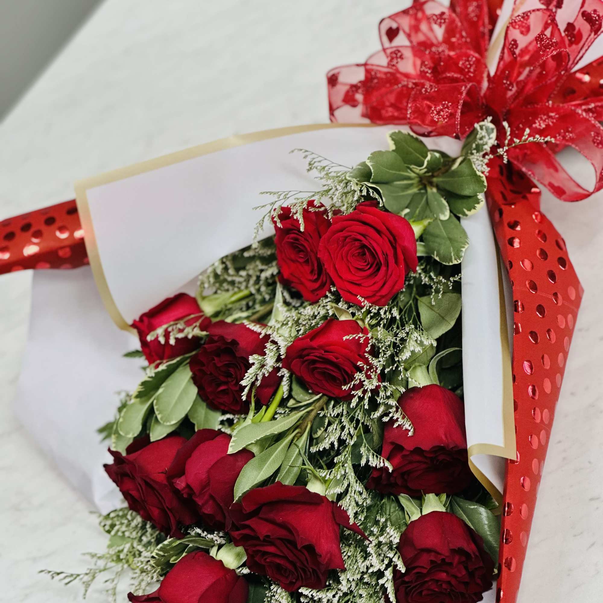 Bouquet of red roses wrapped in white paper with a red ribbon