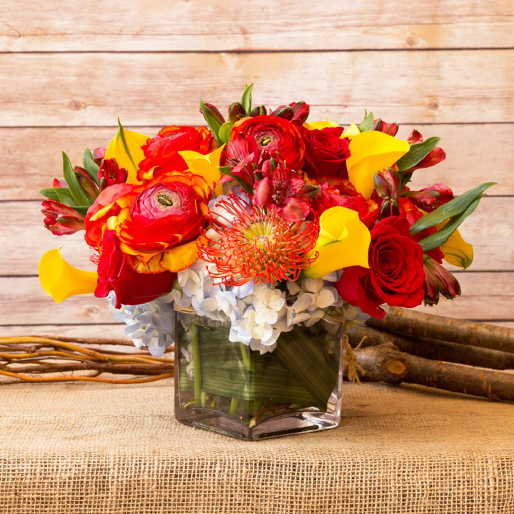 Red and yellow mixed bouquet in a square glass vase