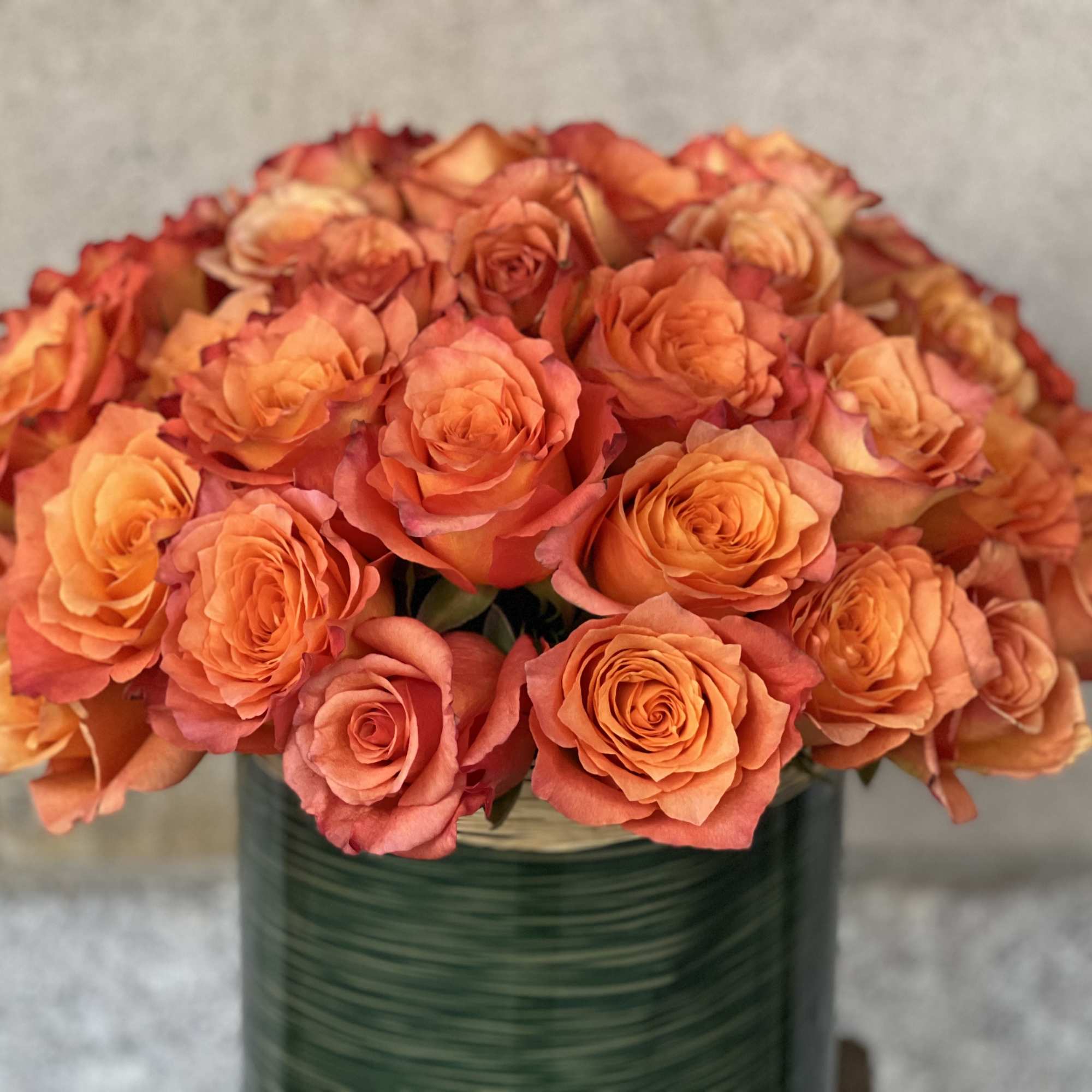 Orange roses arranged in a green vase