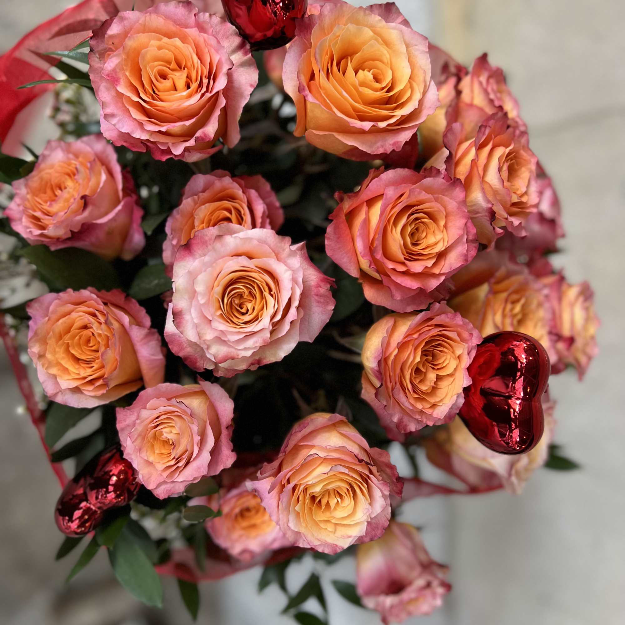 Bouquet of peach and pink roses with red heart balloons