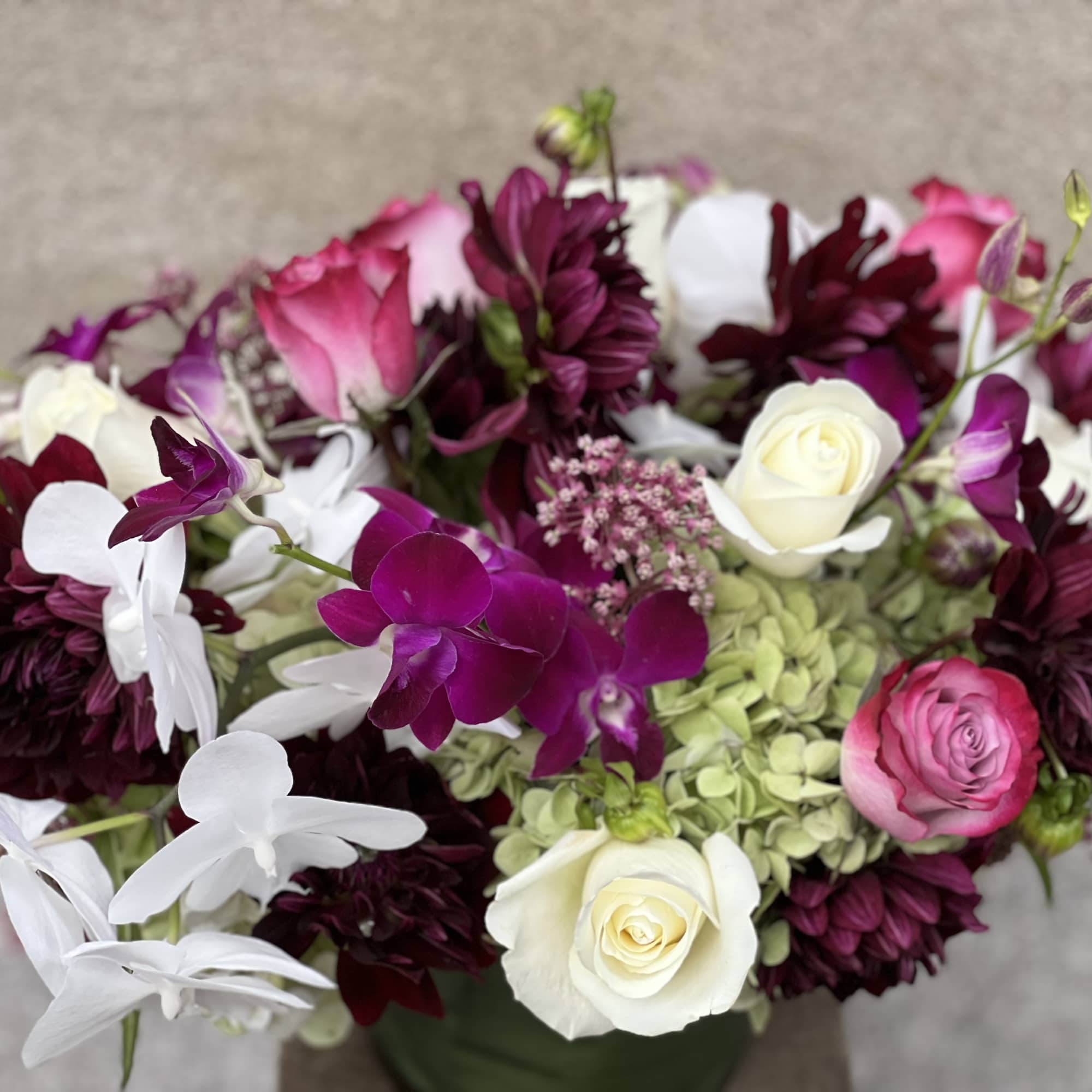 Bouquet of white, pink, and burgundy flowers in a green vase