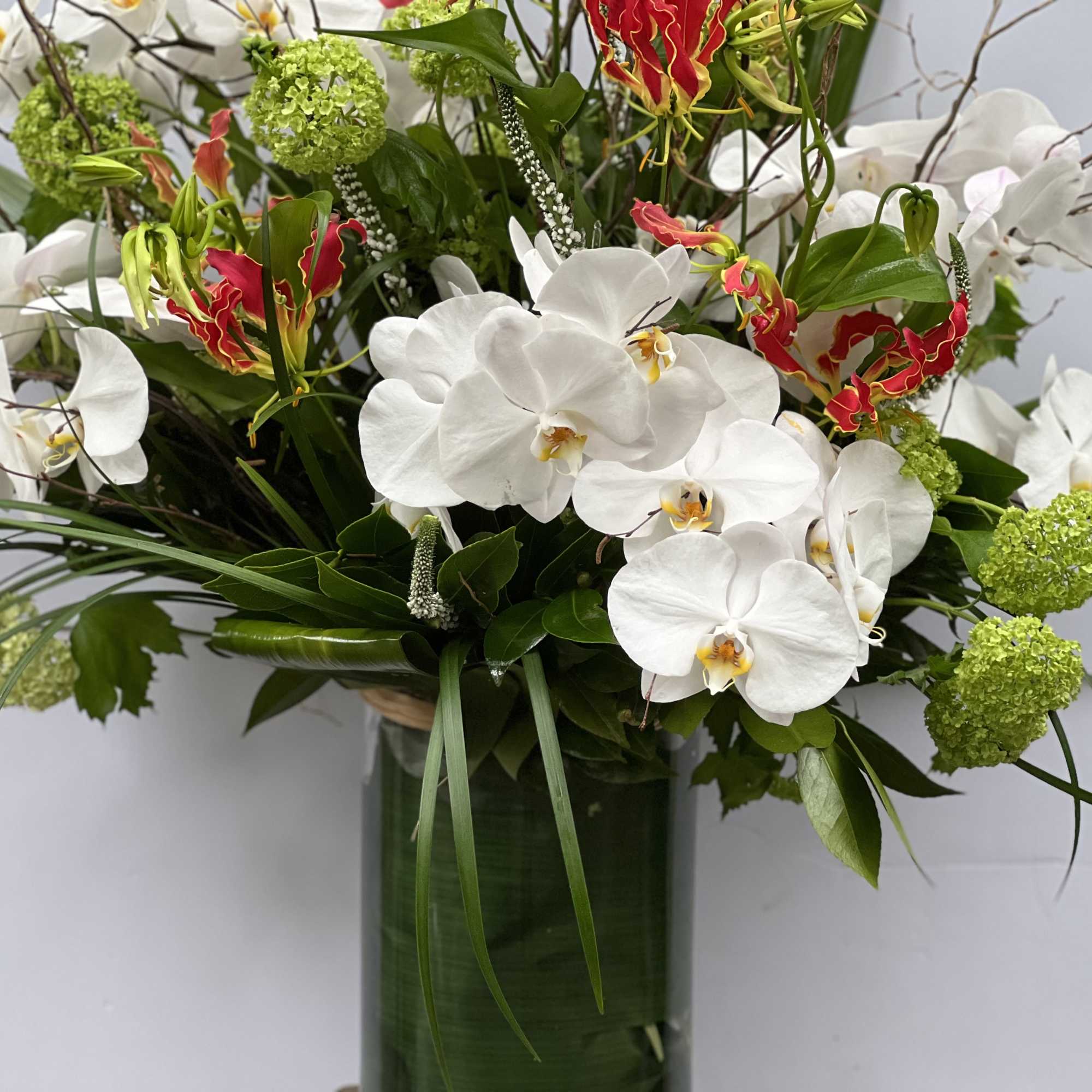White orchids and red tropical flowers in a tall glass vase, photo 10 of 10