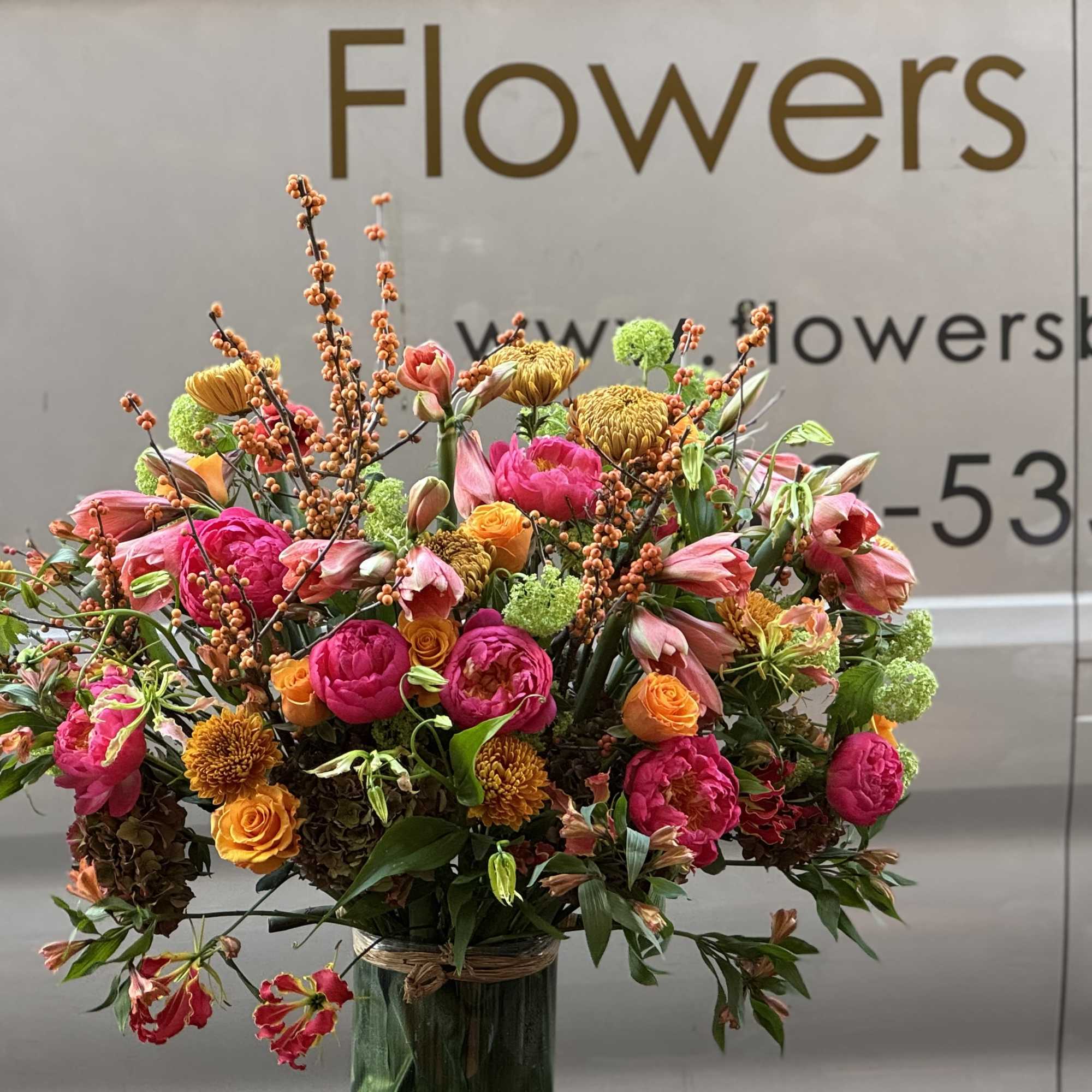 Large mixed bouquet of pink, orange, and green flowers in a glass vase