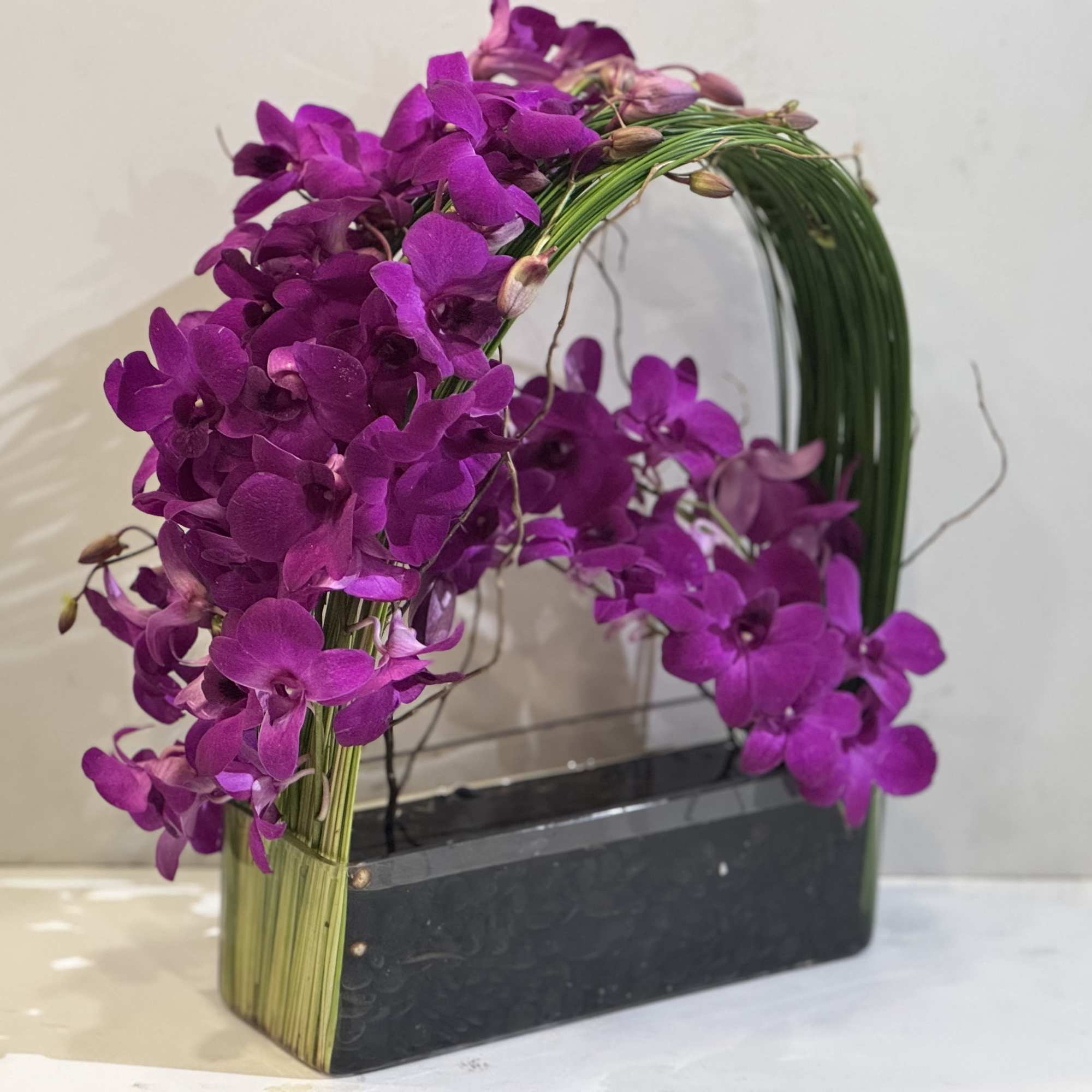 Purple orchid arrangement in a black rectangular container