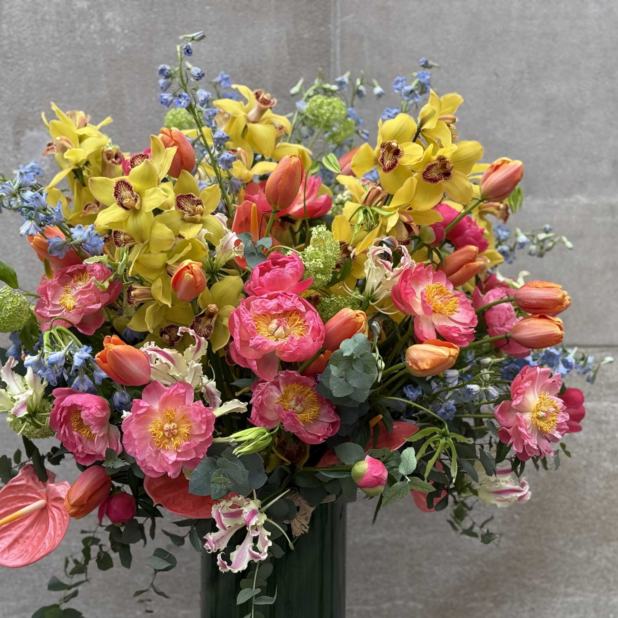 Bright mixed bouquet with pink, yellow, and orange flowers in a tall vase