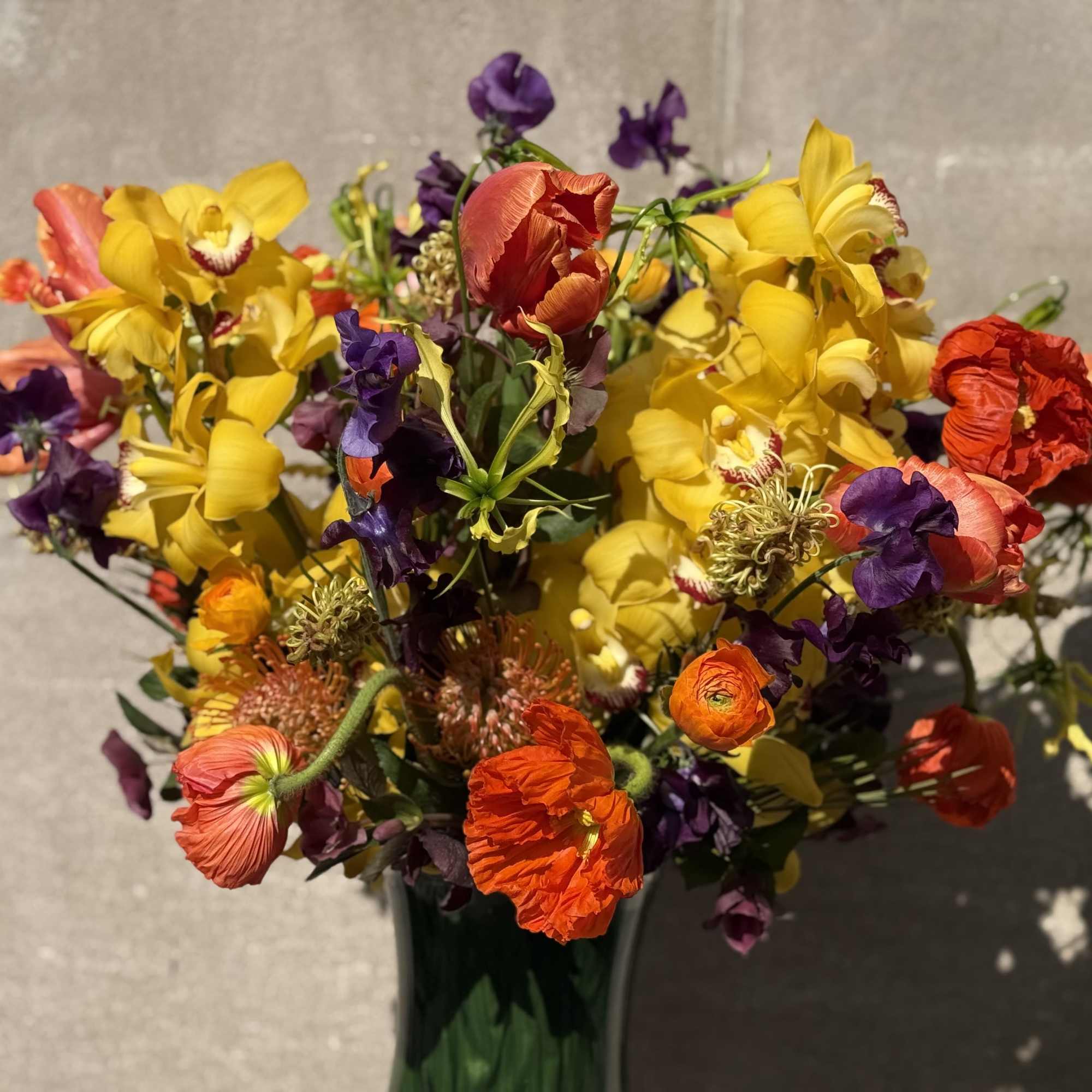Bouquet of yellow, purple, and orange flowers in a glass vase