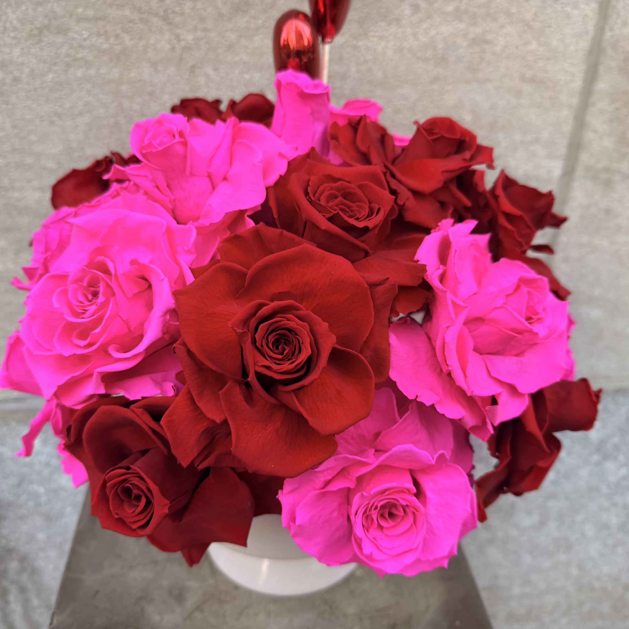 Bouquet of red and hot pink roses in a white vase