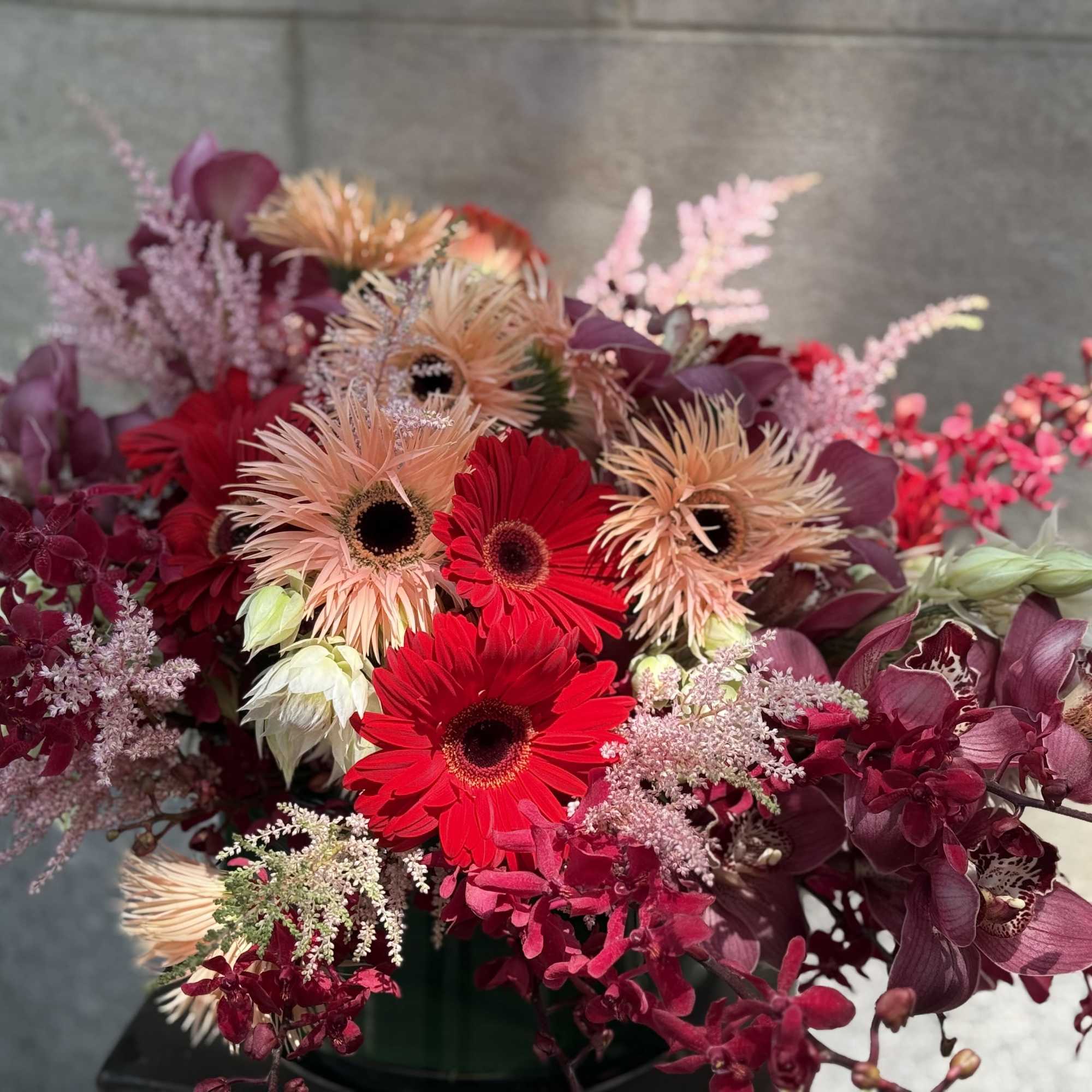 A wacky bouquet of red and peach flowers that&rsquo;s like a party, photo 2 of 4