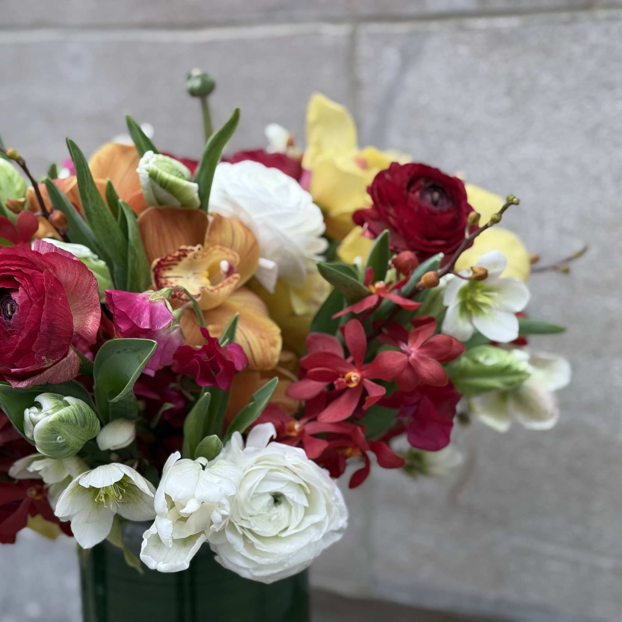 Mixed bouquet of red, white, and yellow flowers in a green vase