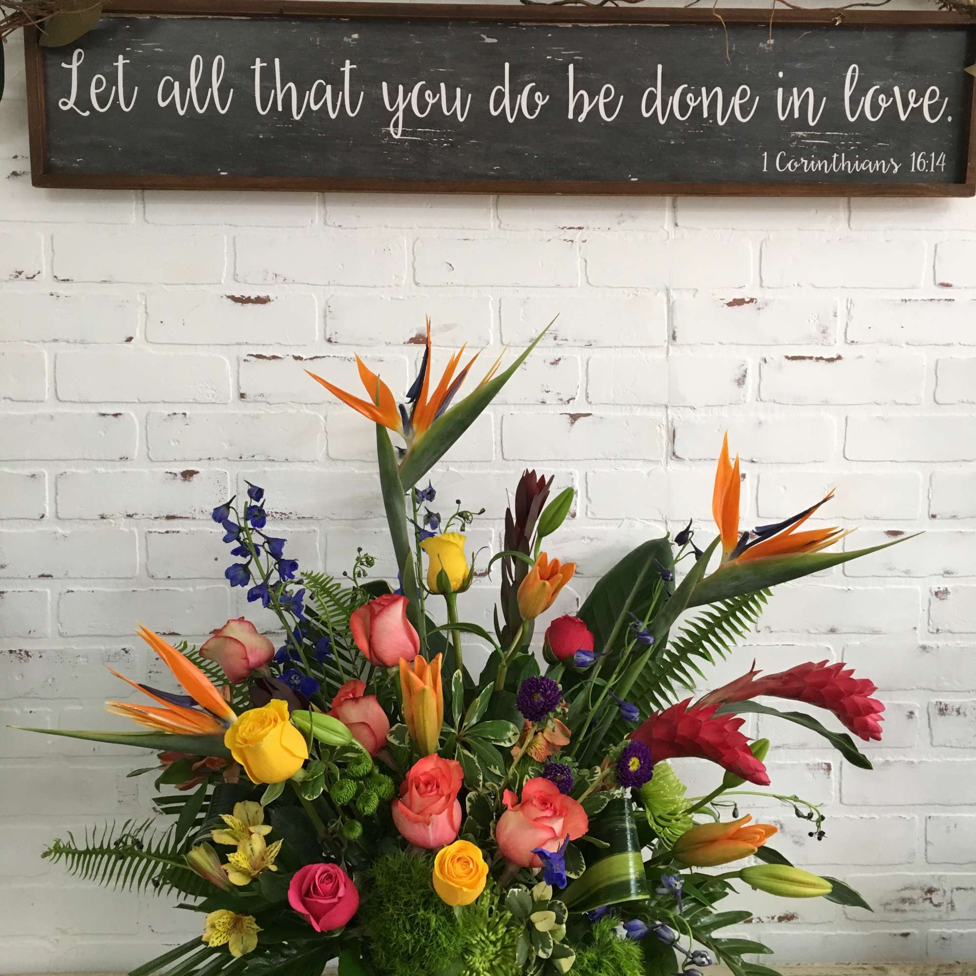 Colorful tropical floral arrangement in a square glass vase