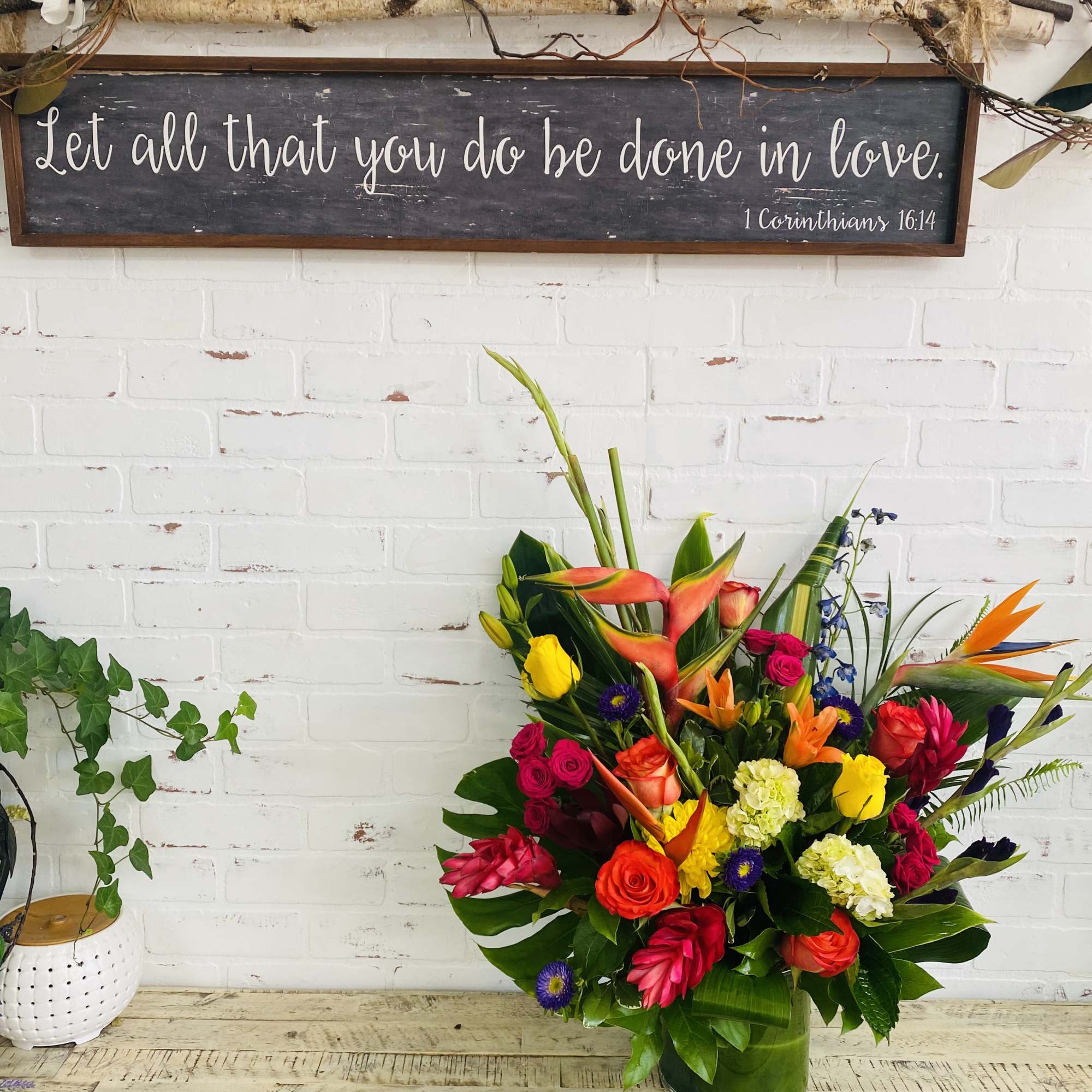 Bright mixed bouquet in a glass vase with tropical blooms and roses