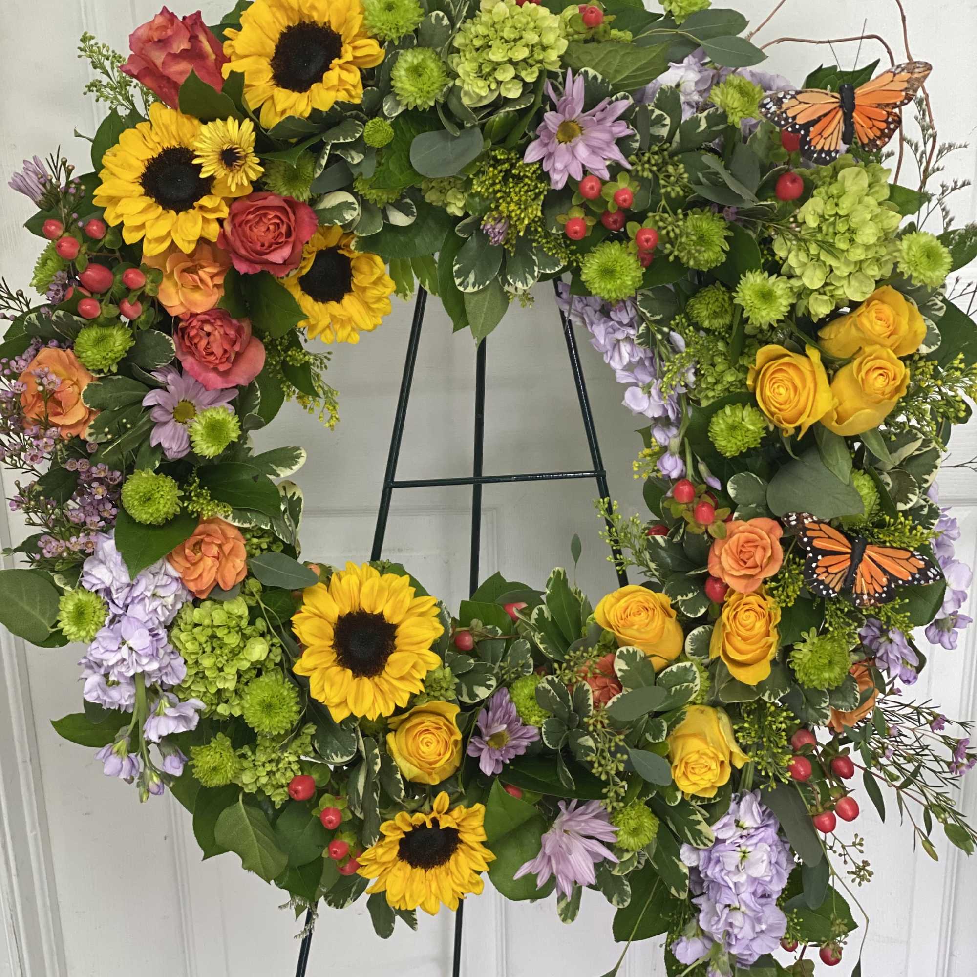 Heart-shaped floral wreath with sunflowers, roses, and butterflies