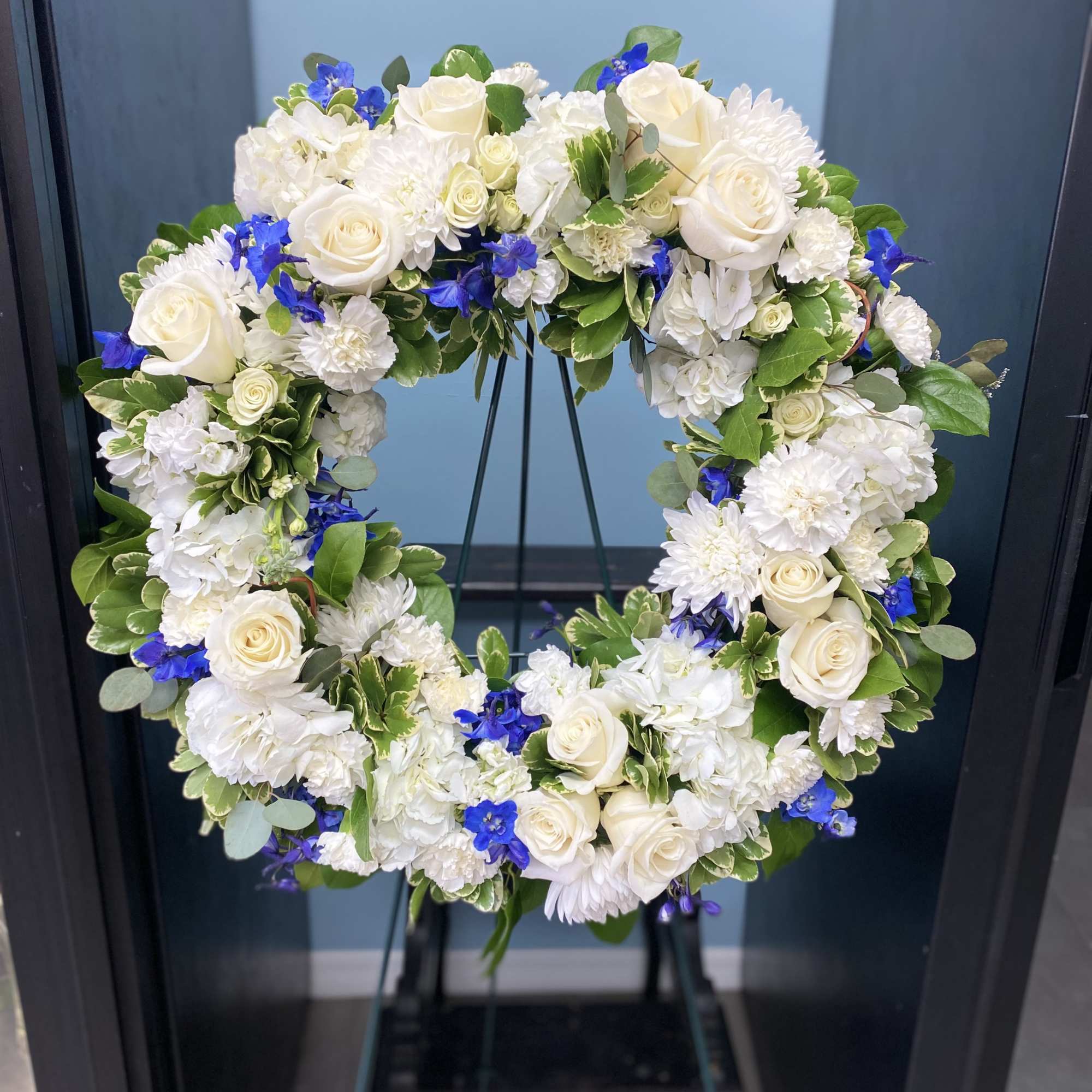 White and blue floral wreath on a stand