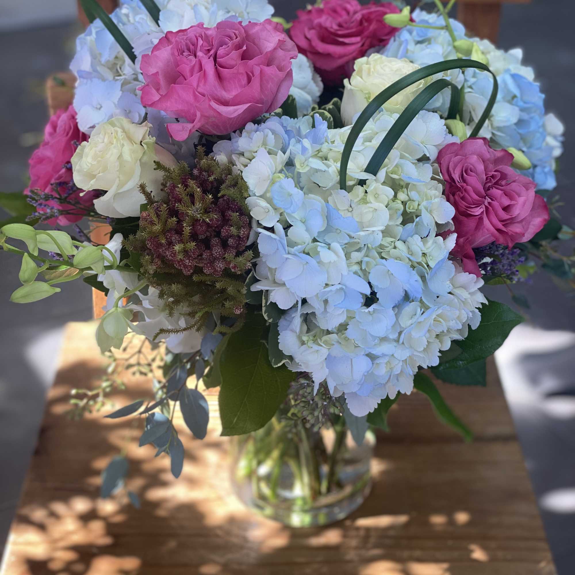 Pink roses and blue hydrangeas arranged in a glass vase