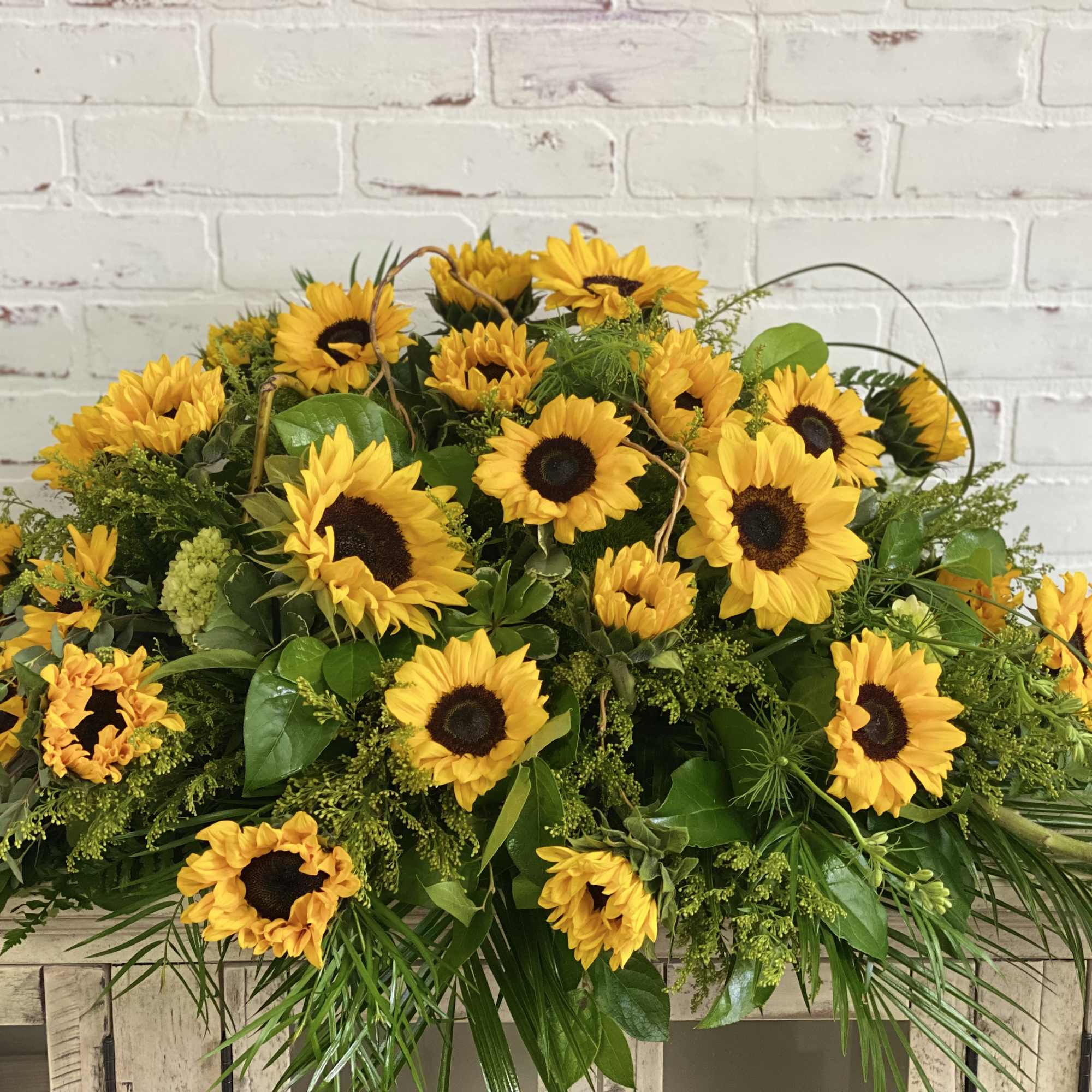 Large sunflower arrangement with greenery on a wooden table