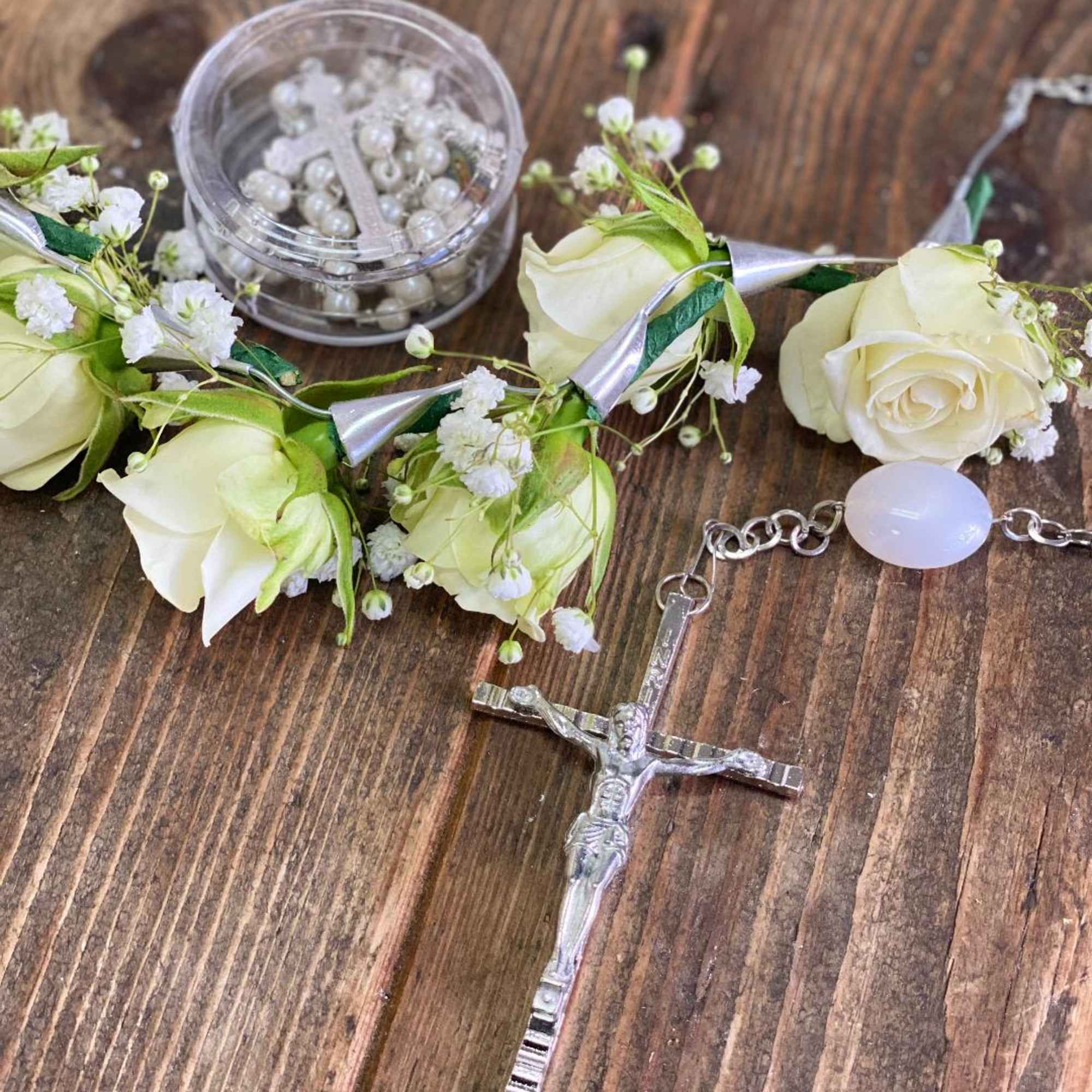 White rose floral bracelet with a silver crucifix and pearl accents