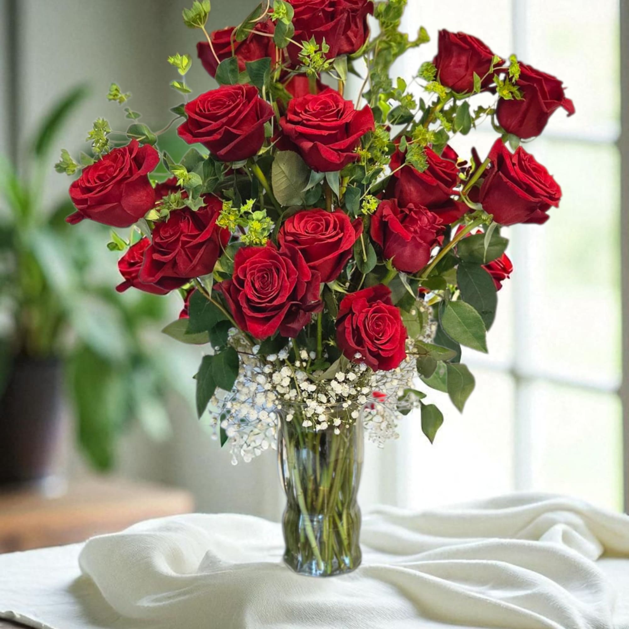 Red roses arranged in a clear glass vase with baby's breath