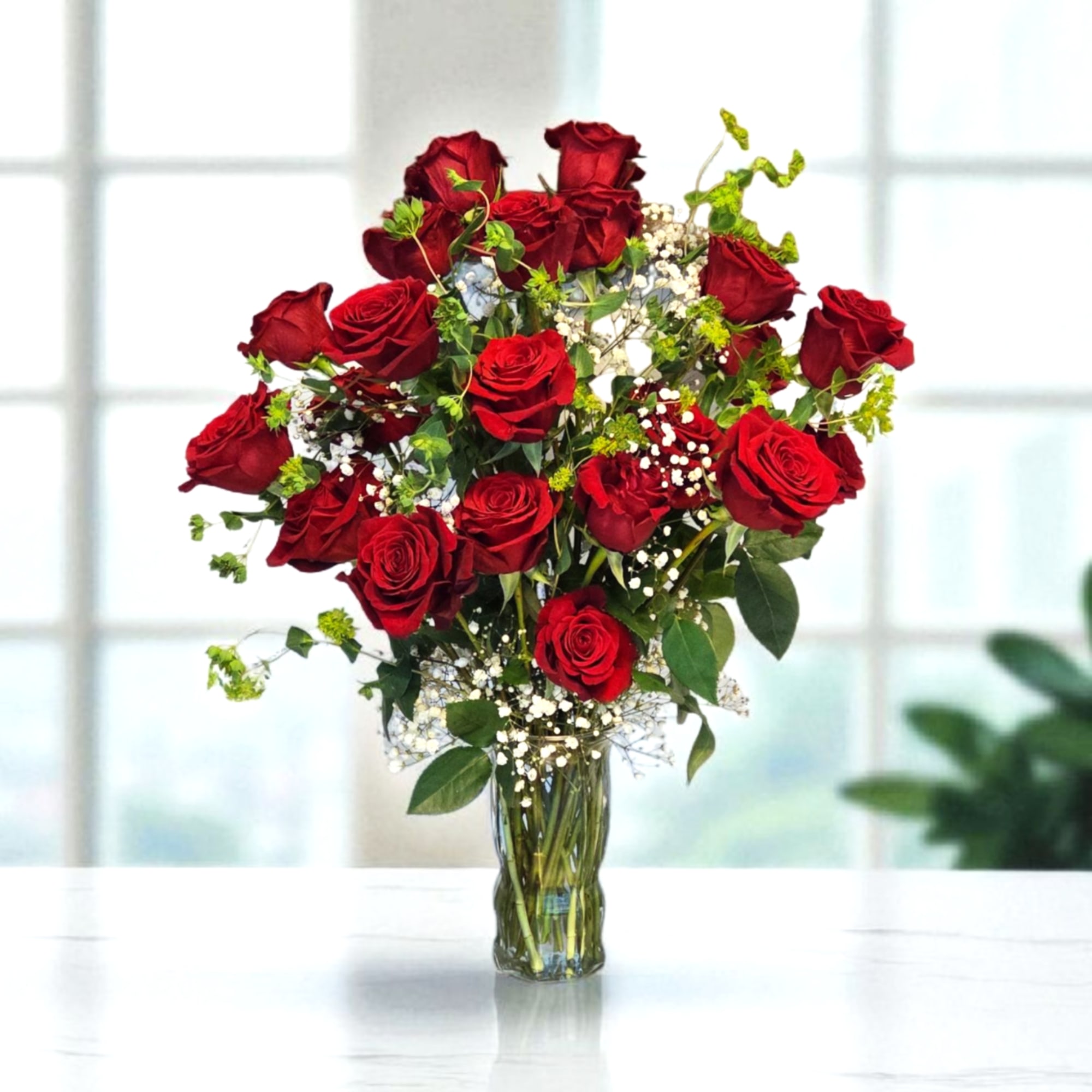 Red roses arranged in a clear glass vase with white filler flowers